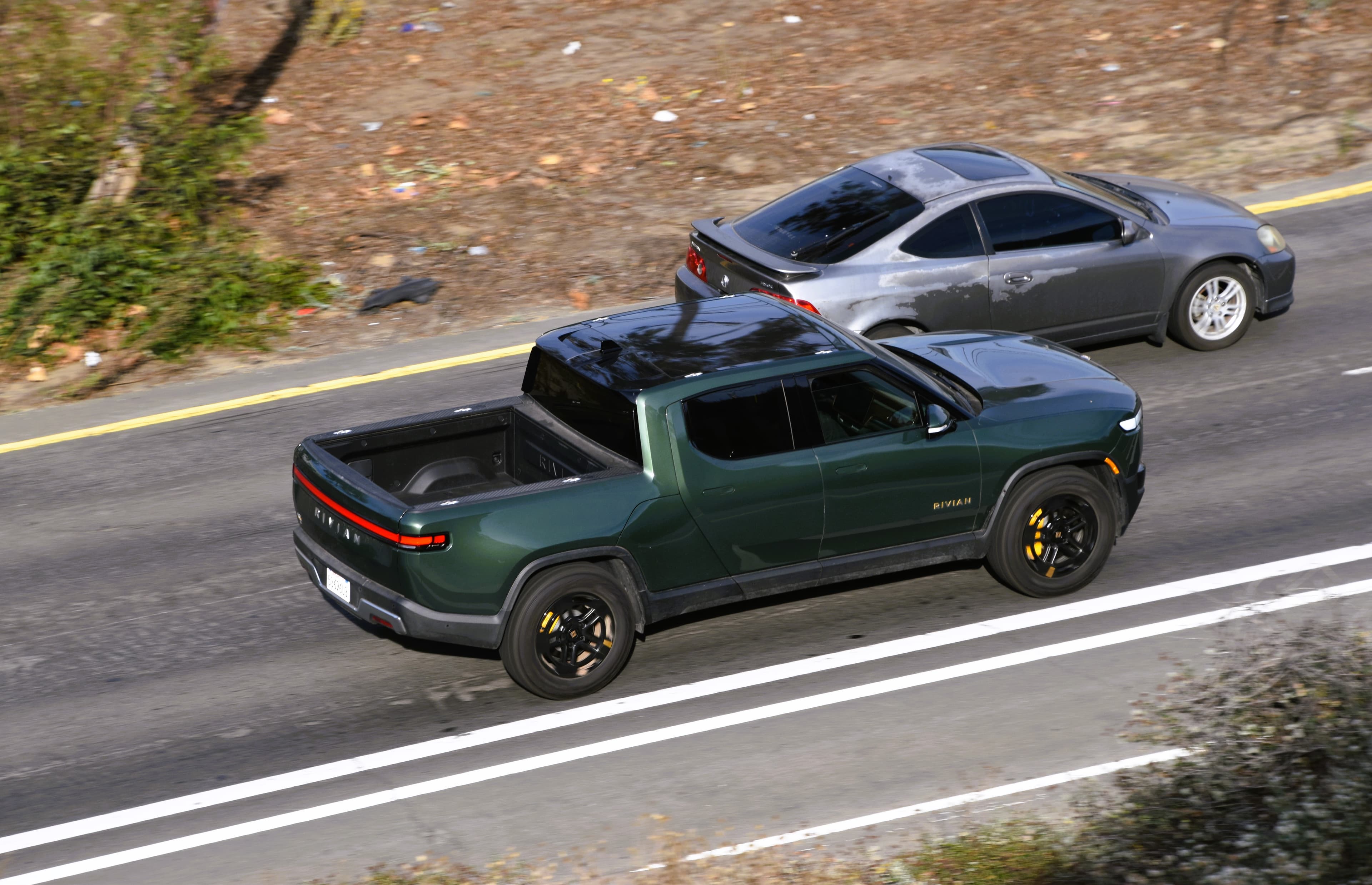 Rivian R1T estacionada em ambiente natural, vista traseira com barra de luz