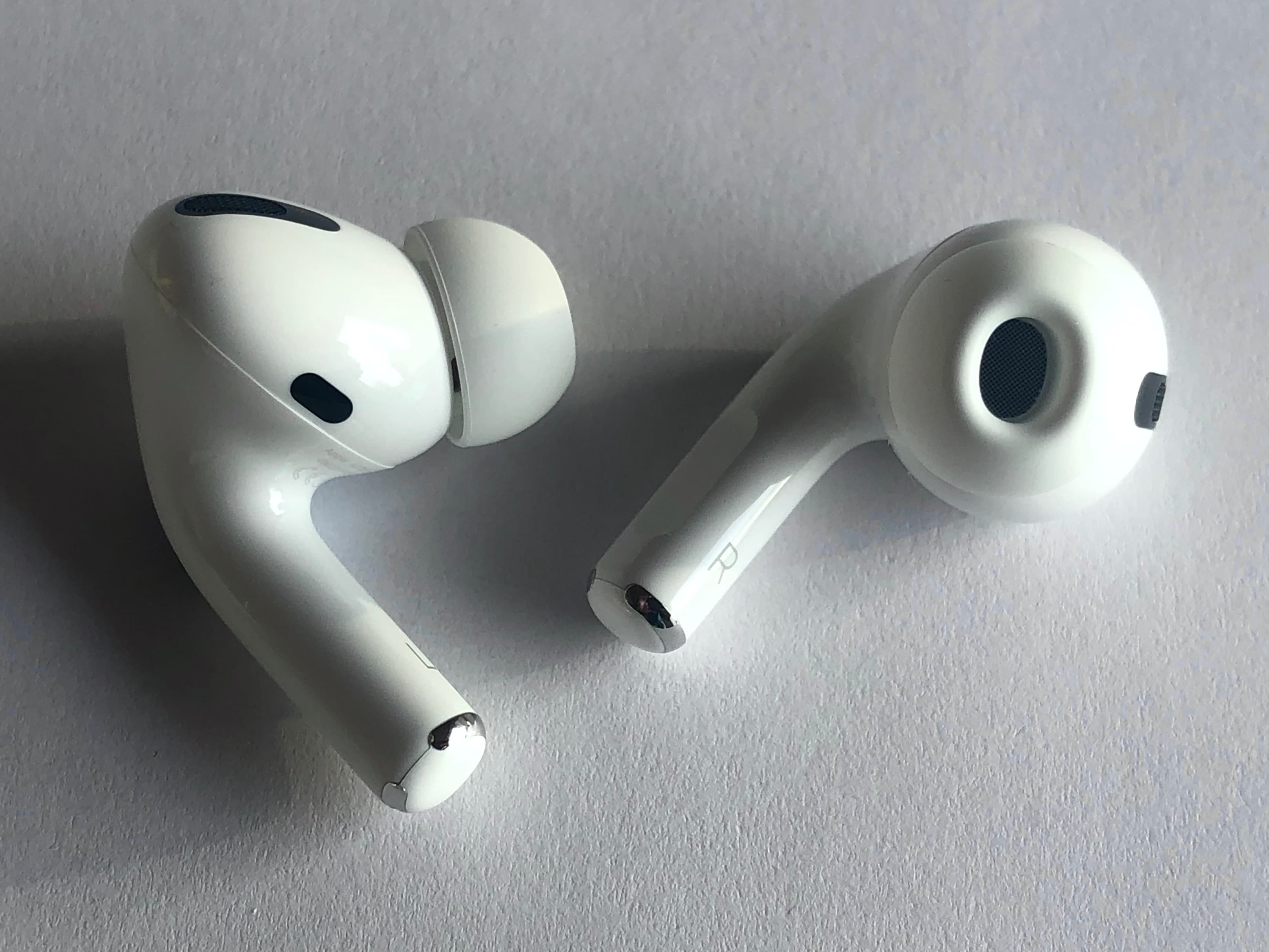 AirPods Pro em close, duas unidades sobre superfície clara, foco no design e nos microfones