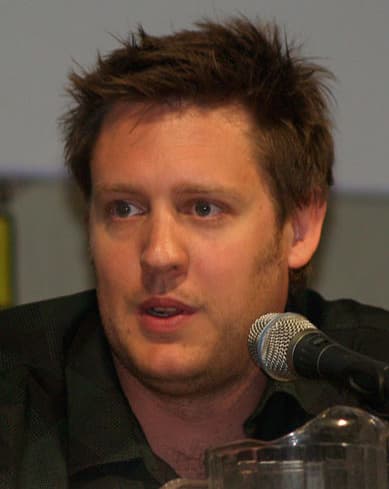Neill Blomkamp falando ao microfone em 2009, close do diretor