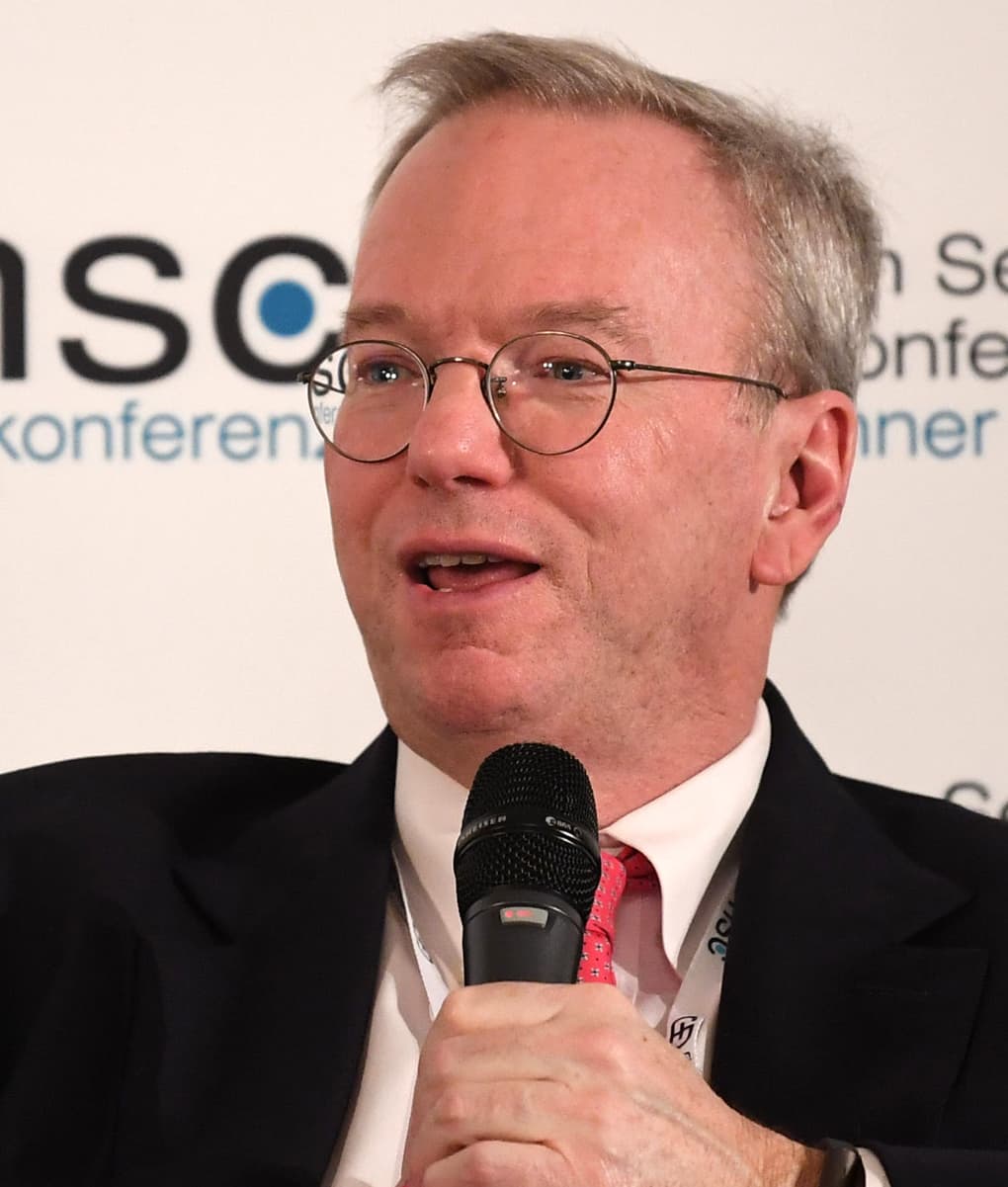 Retrato de Eric Schmidt falando em evento, microfone na mão
