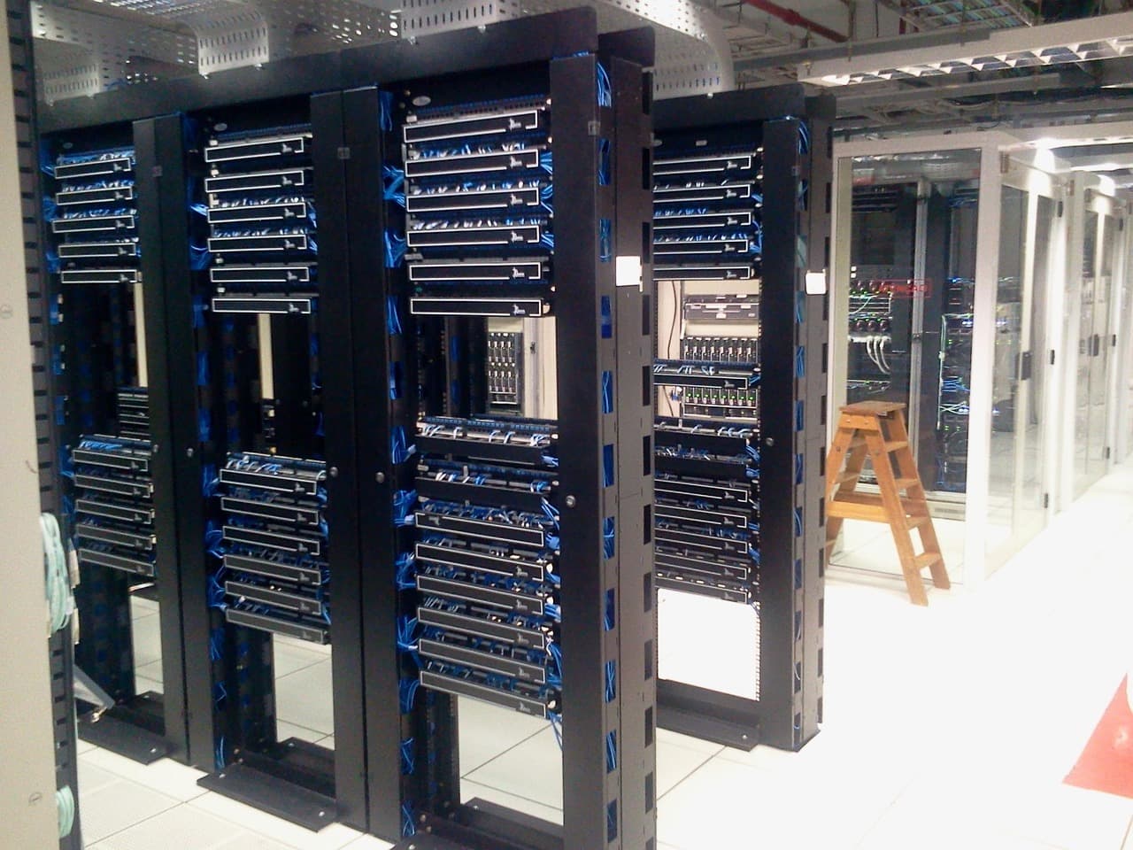 Corredor de data center com racks de servidores, simbolizando infraestrutura de IA