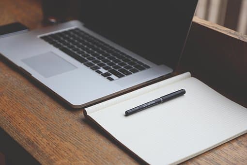 Laptop e caderno em mesa de trabalho, conceito de produtividade com IA