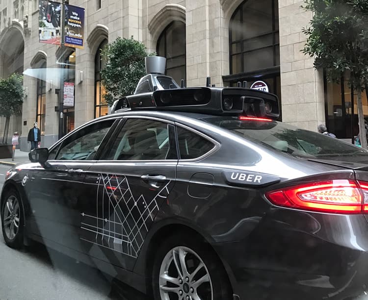 Veículo de testes da Uber com sensor lidar no teto, em rua urbana