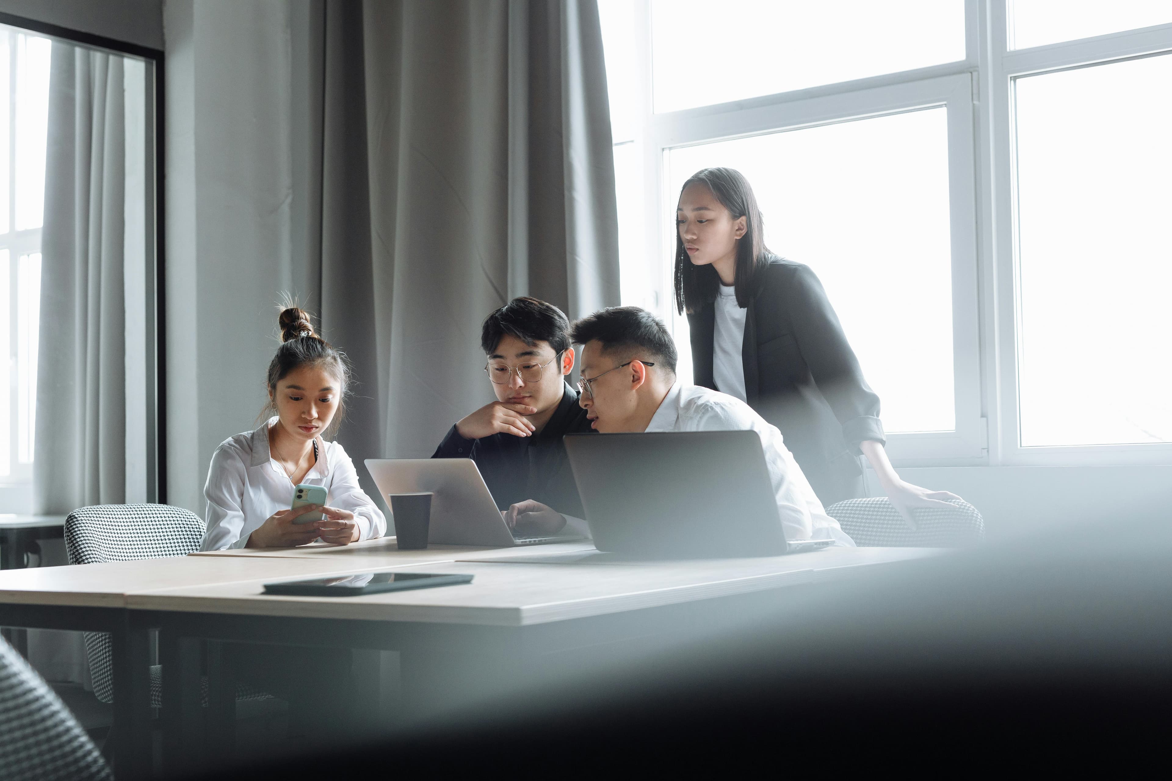 Equipe colaborando em escritório com laptops, simbolizando apps interativos no Claude
