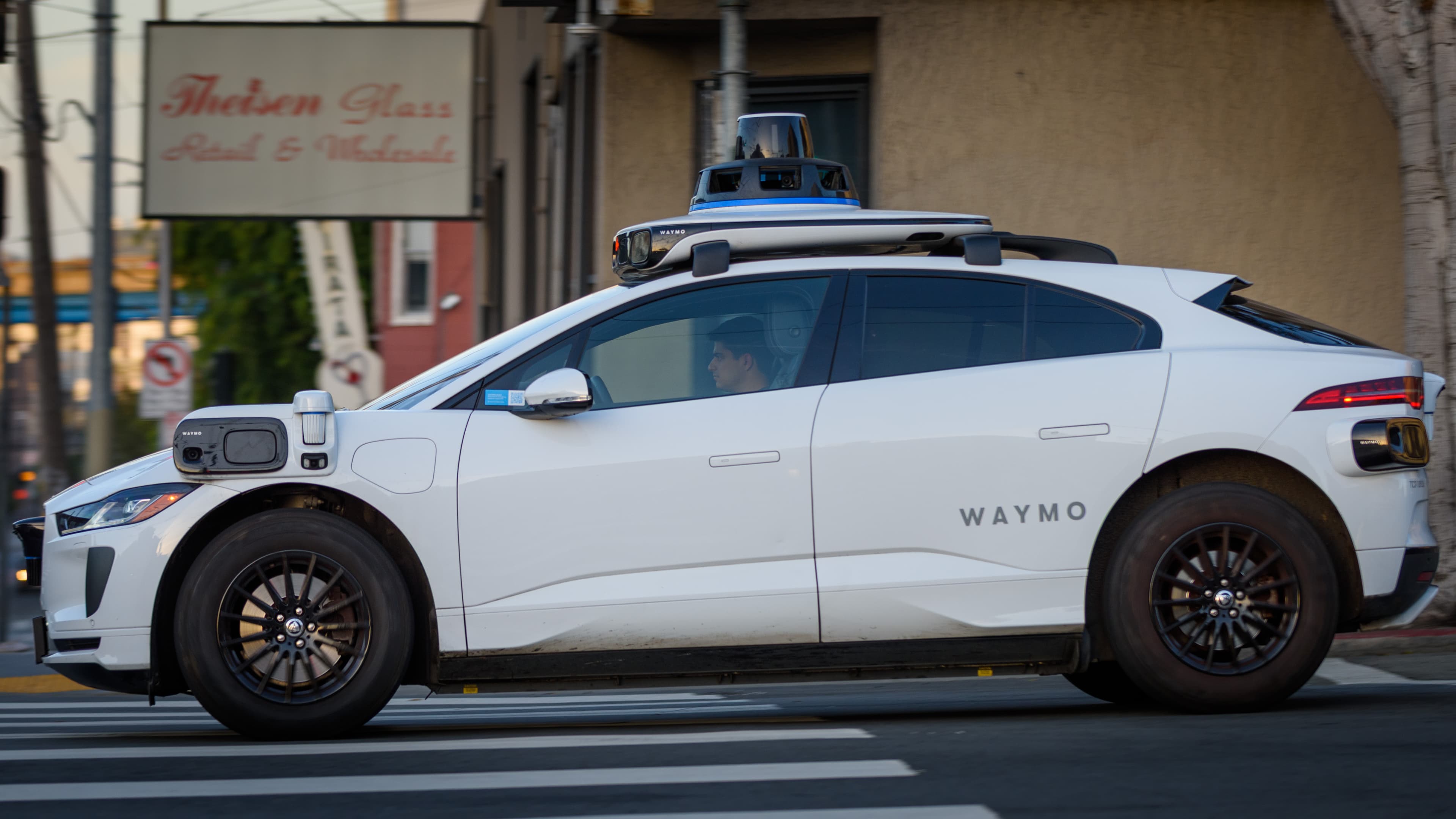 Carro autônomo Waymo Jaguar I-Pace circulando em área urbana