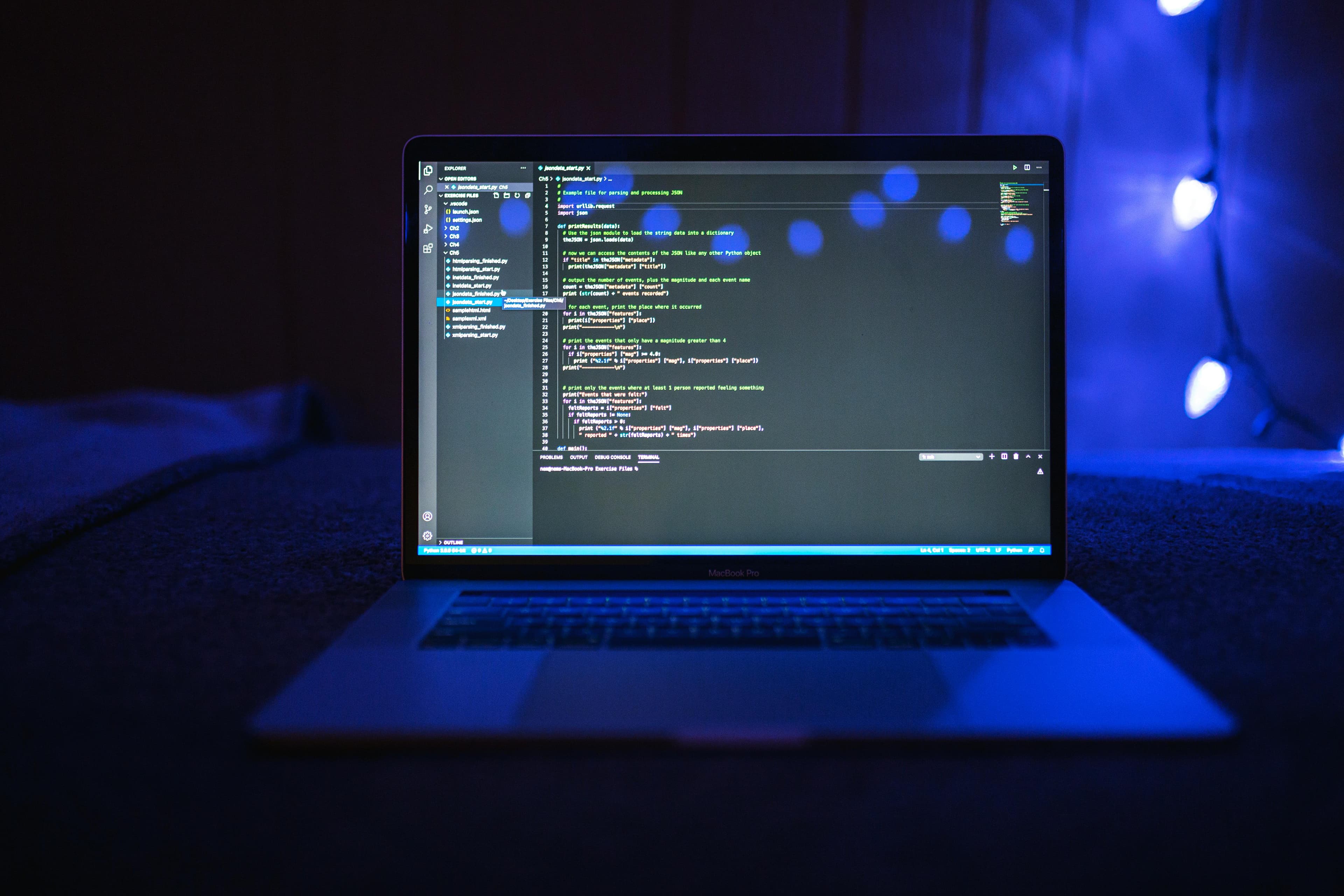 Tela de laptop exibindo código com iluminação azul, destacando tecnologia e programação