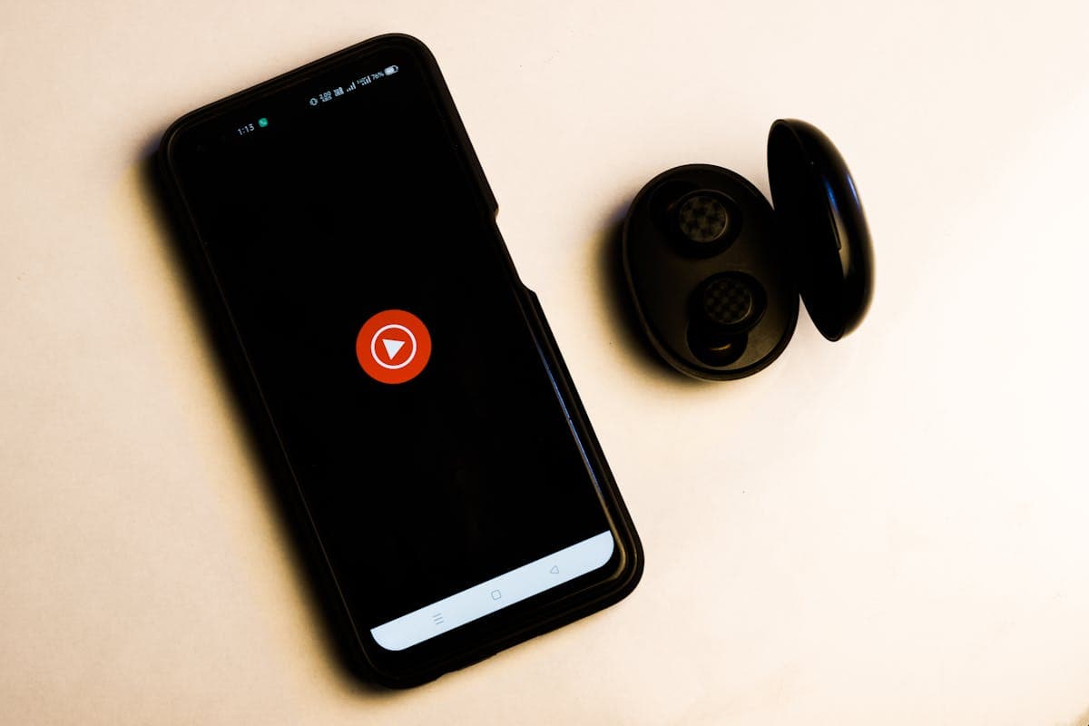 Logotipo do YouTube Music exibido na tela de um smartphone ao lado de fones