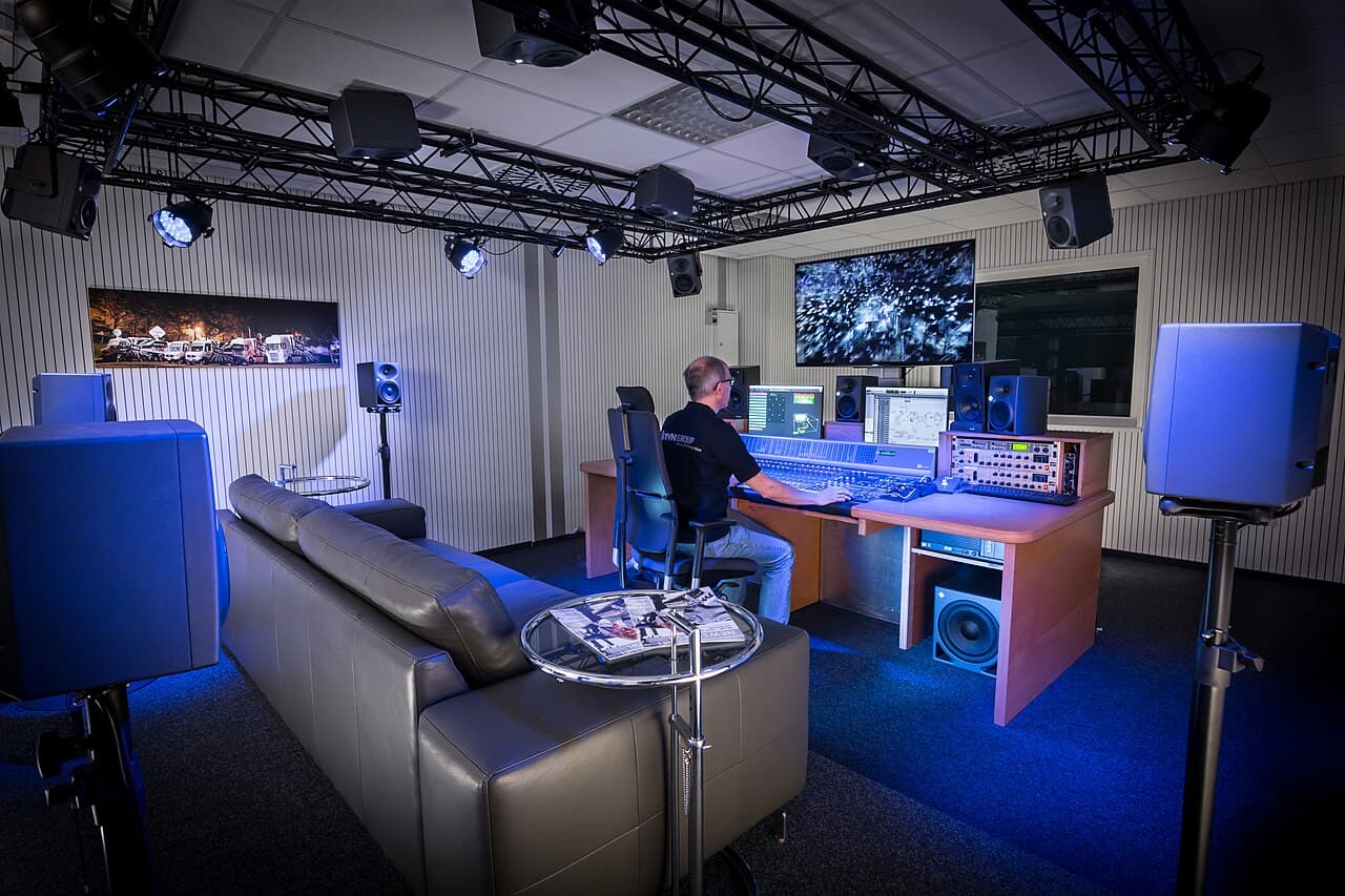 Estúdio de áudio Dolby Atmos com produtor em frente a monitores e equipamentos