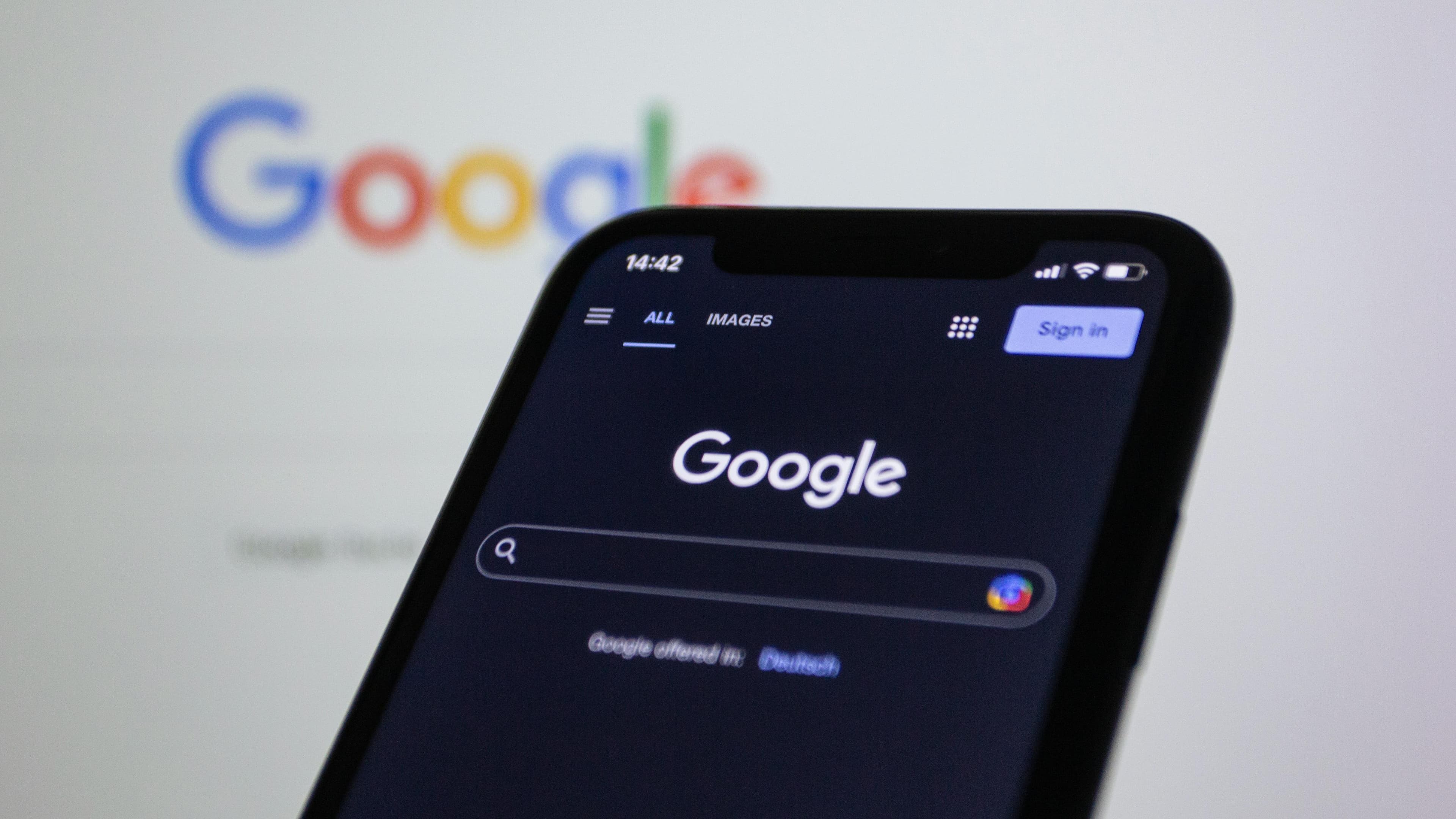Smartphone exibindo a busca do Google em modo escuro, simbolizando o AI Mode