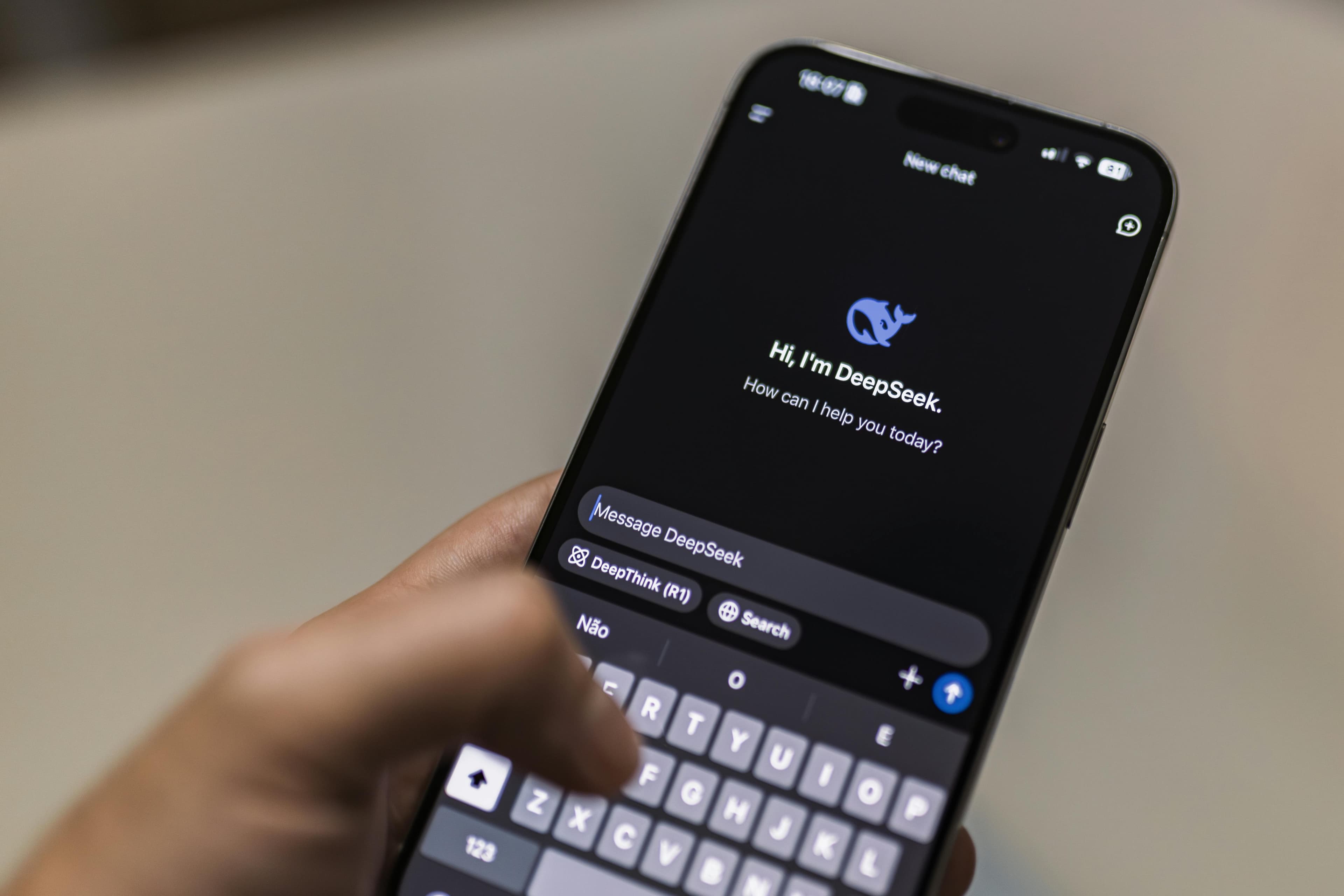 Mão segurando smartphone exibindo interface de chatbot de IA em modo escuro