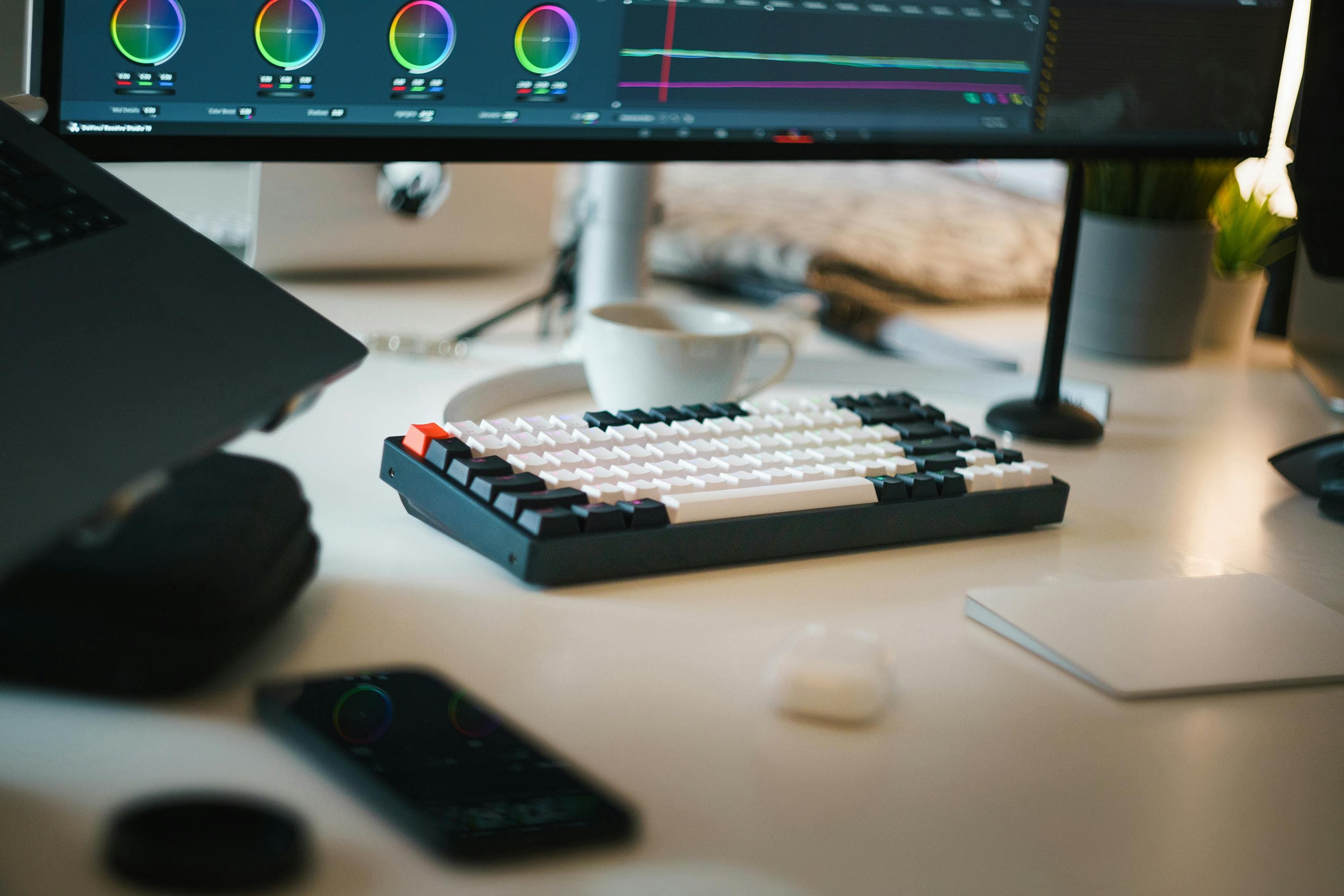 Setup de edição de vídeo com teclado mecânico e monitor ultrawide