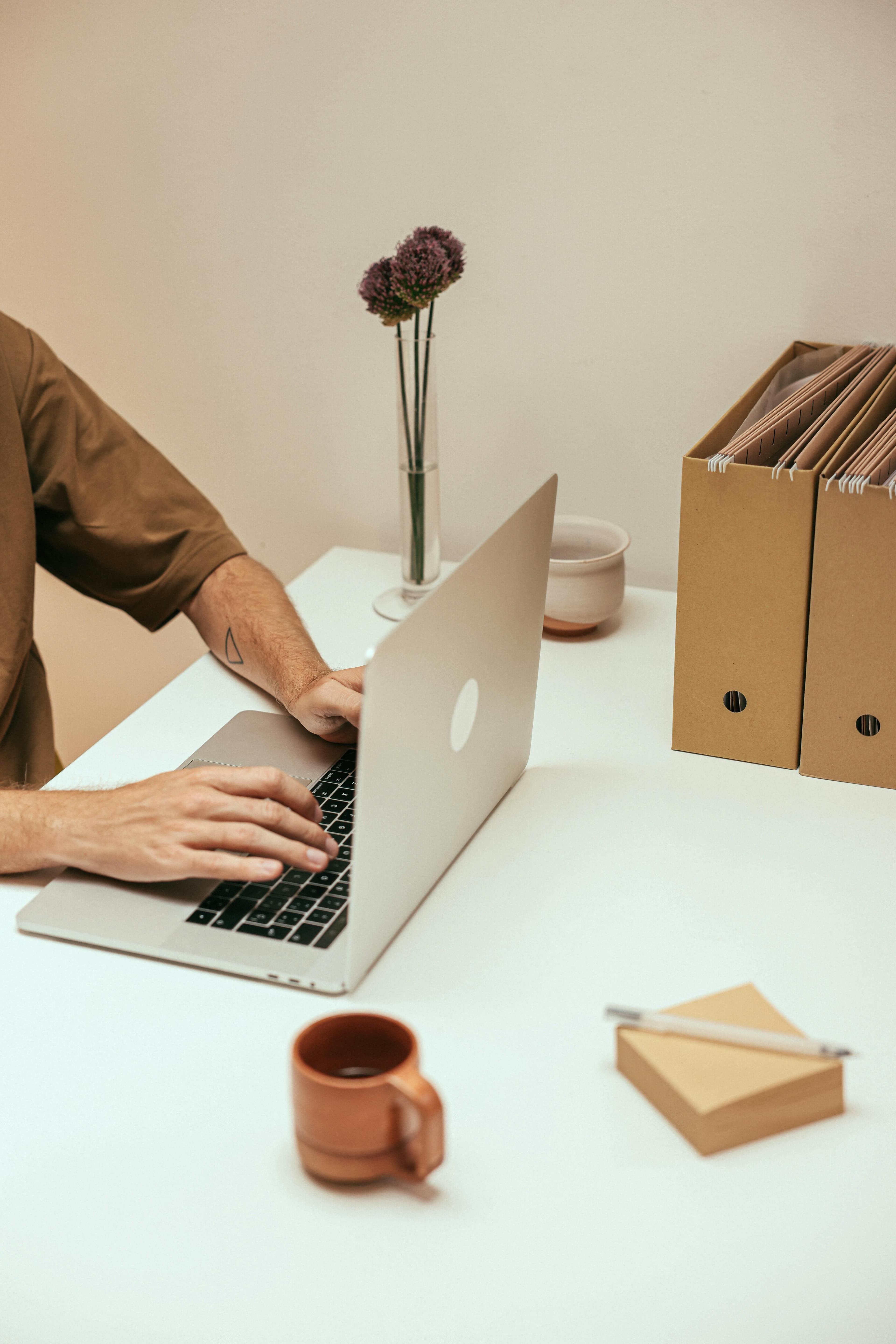 Mãos digitando em laptop em mesa de escritório minimalista