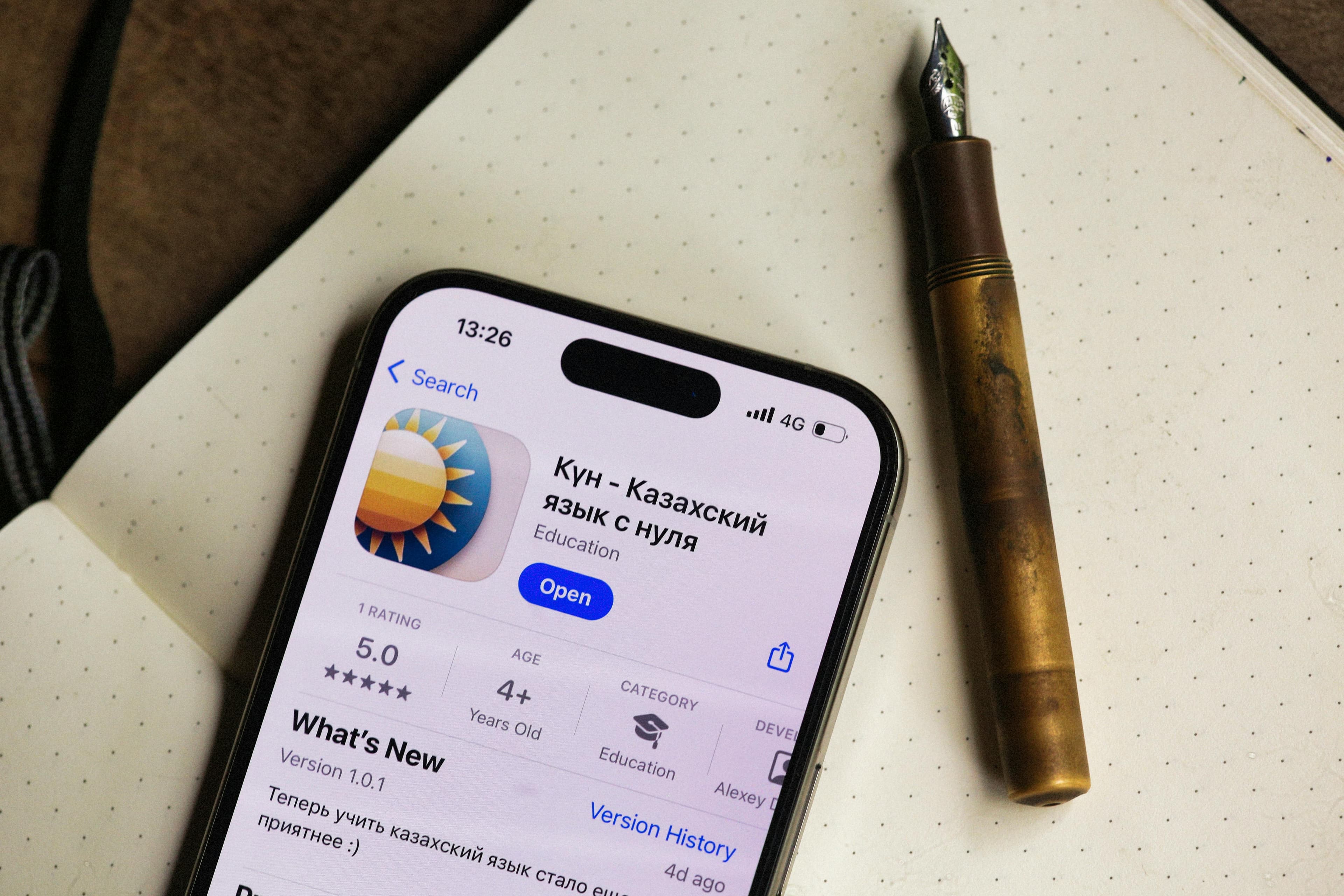 Smartphone com app de idiomas aberto ao lado de uma caneta