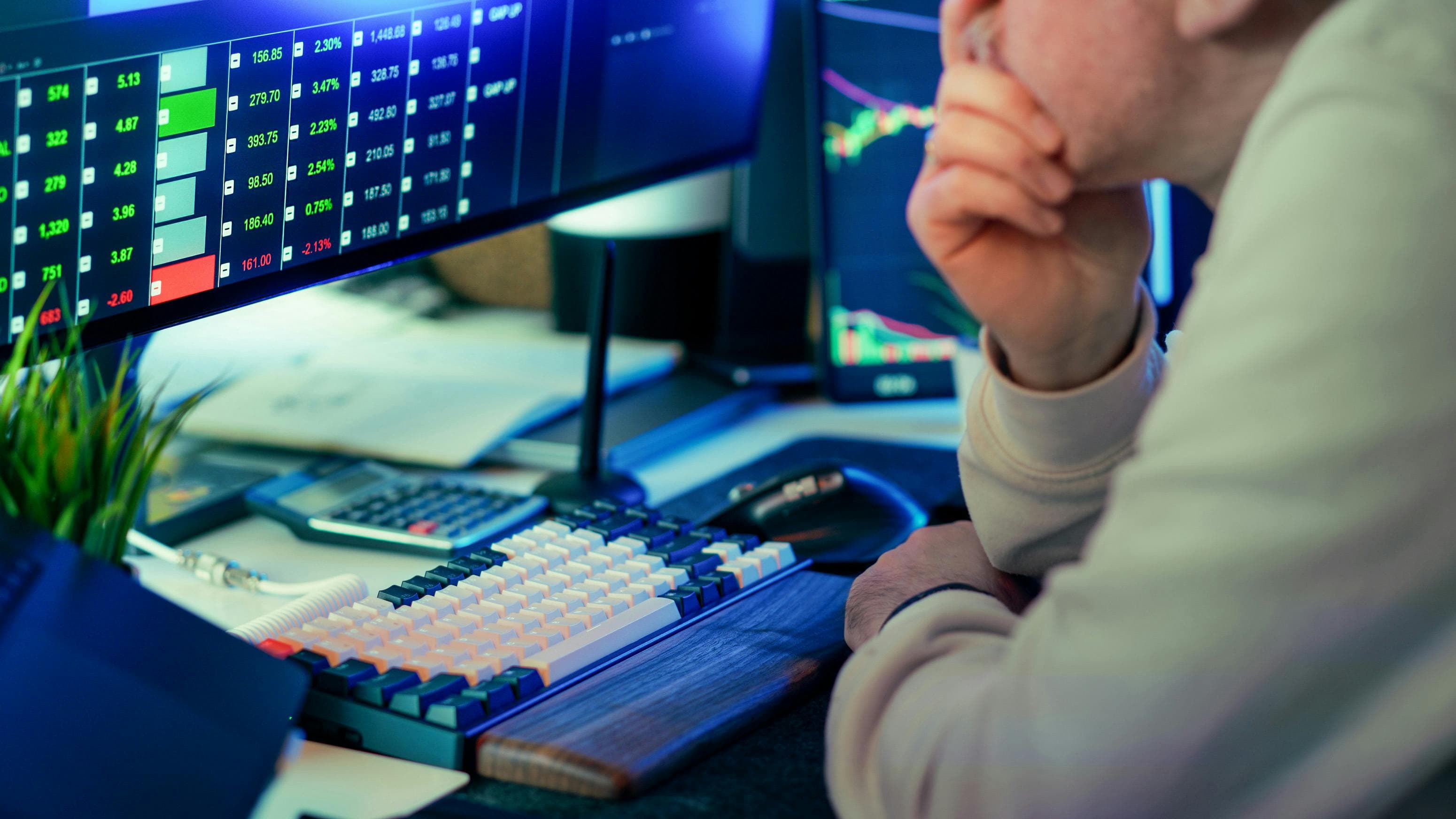 Setup de análise financeira com monitores exibindo cotações e gráficos
