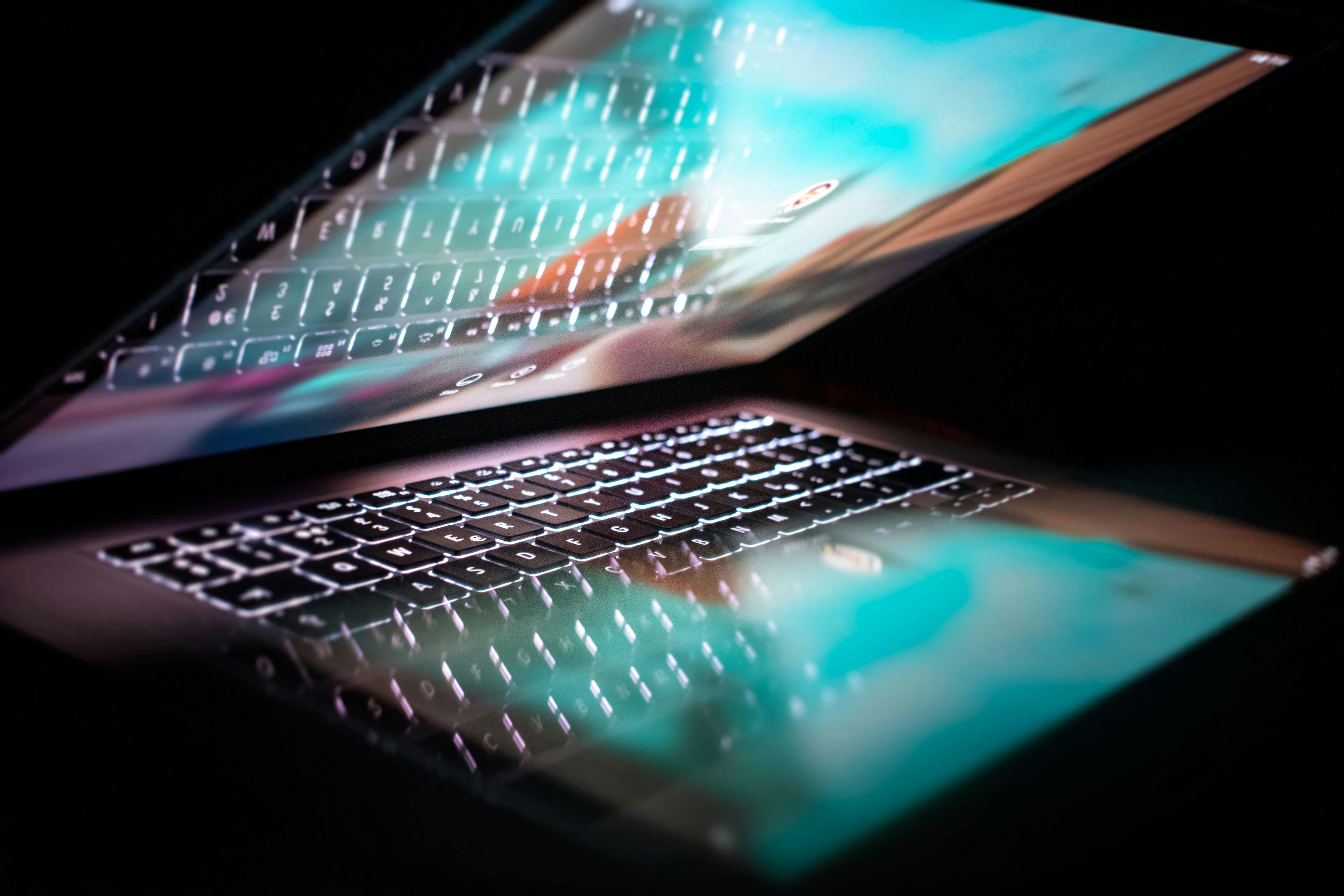 MacBook em close com reflexo da tela, ilustrando uso em modo clamshell