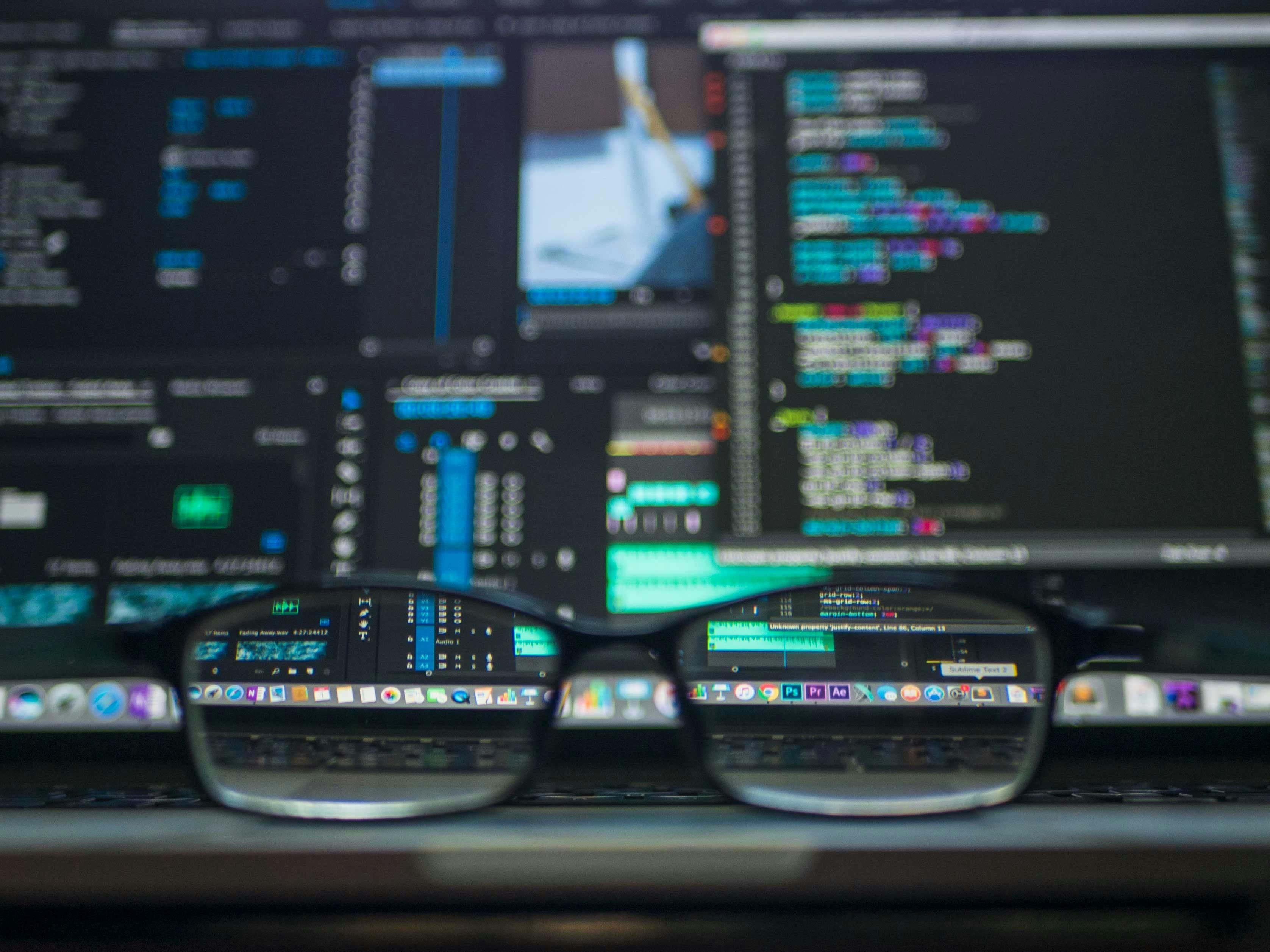 Óculos refletindo código em tela de desenvolvedor, representando sessões paralelas no terminal