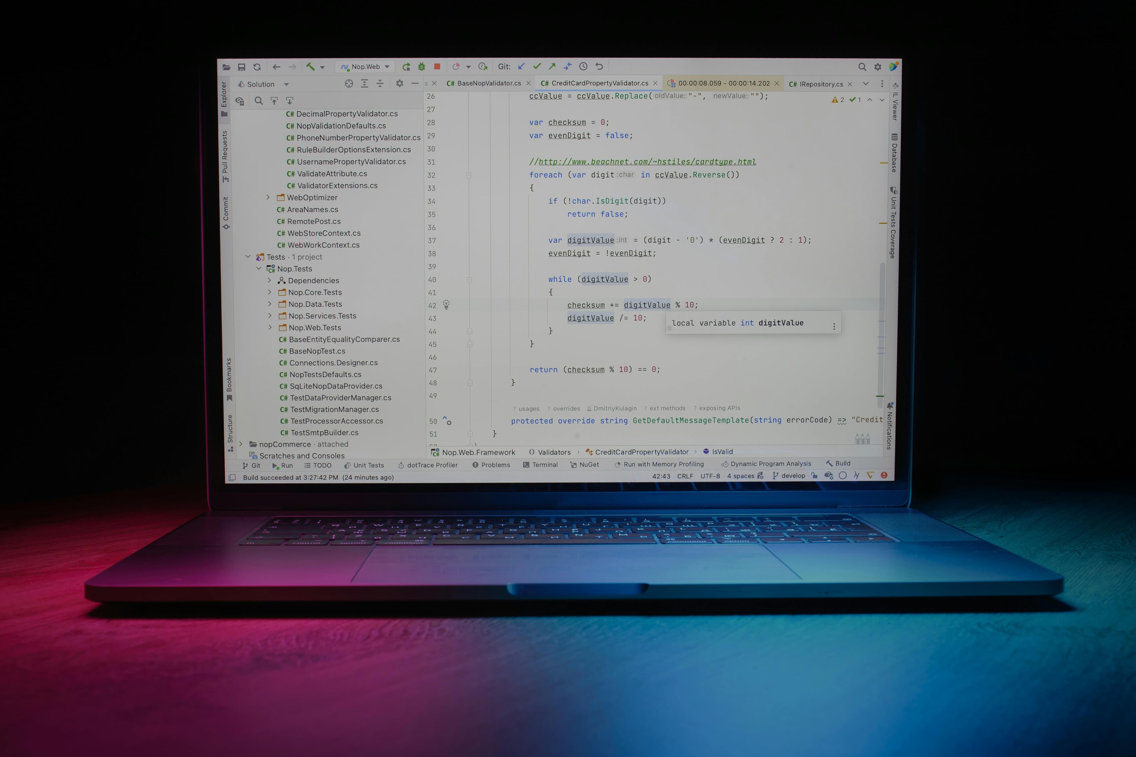 Laptop com editor de código mostrando linhas de código, iluminação colorida ao fundo