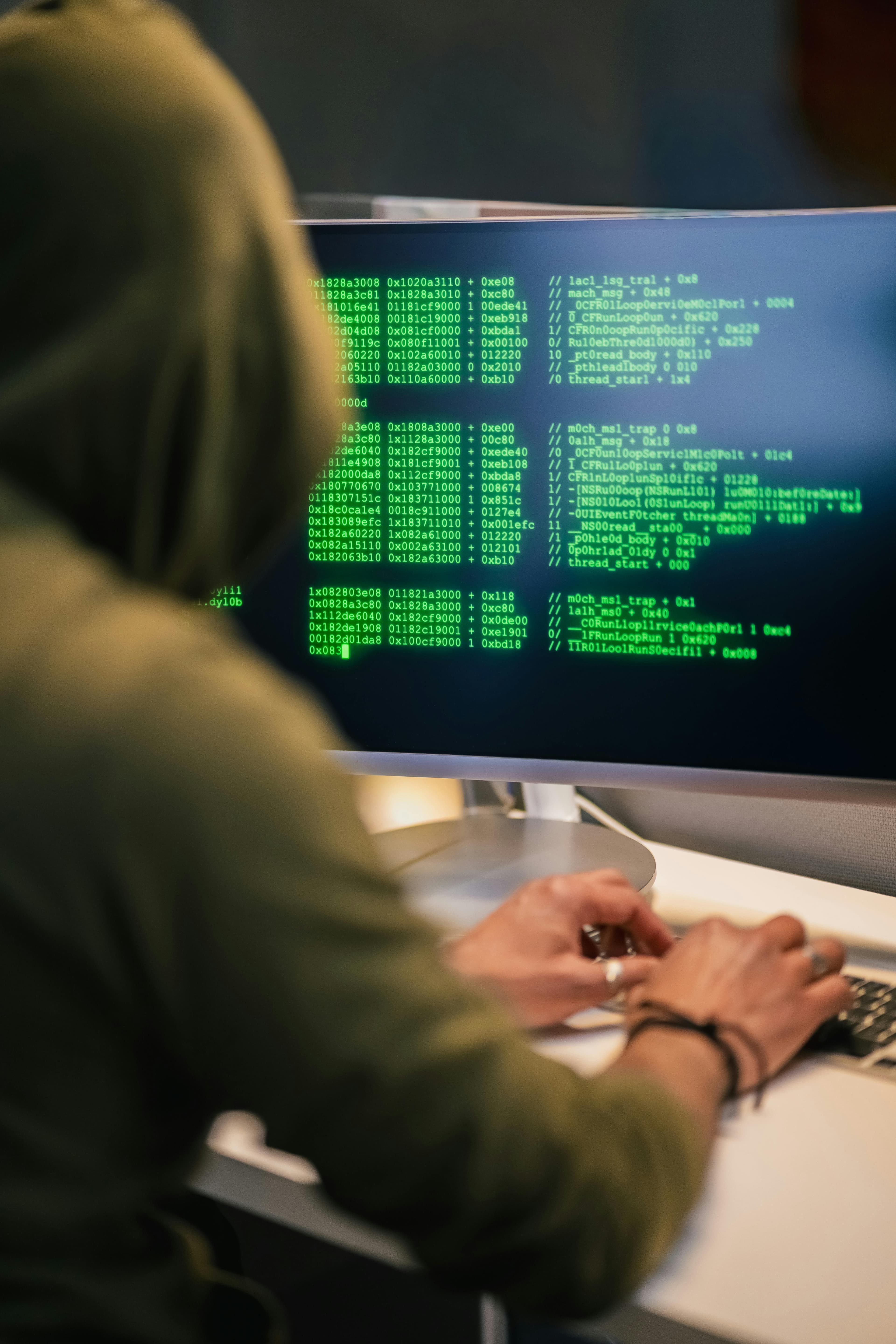 Pessoa diante de monitor com código verde, simbolizando cibersegurança e análise de vulnerabilidades