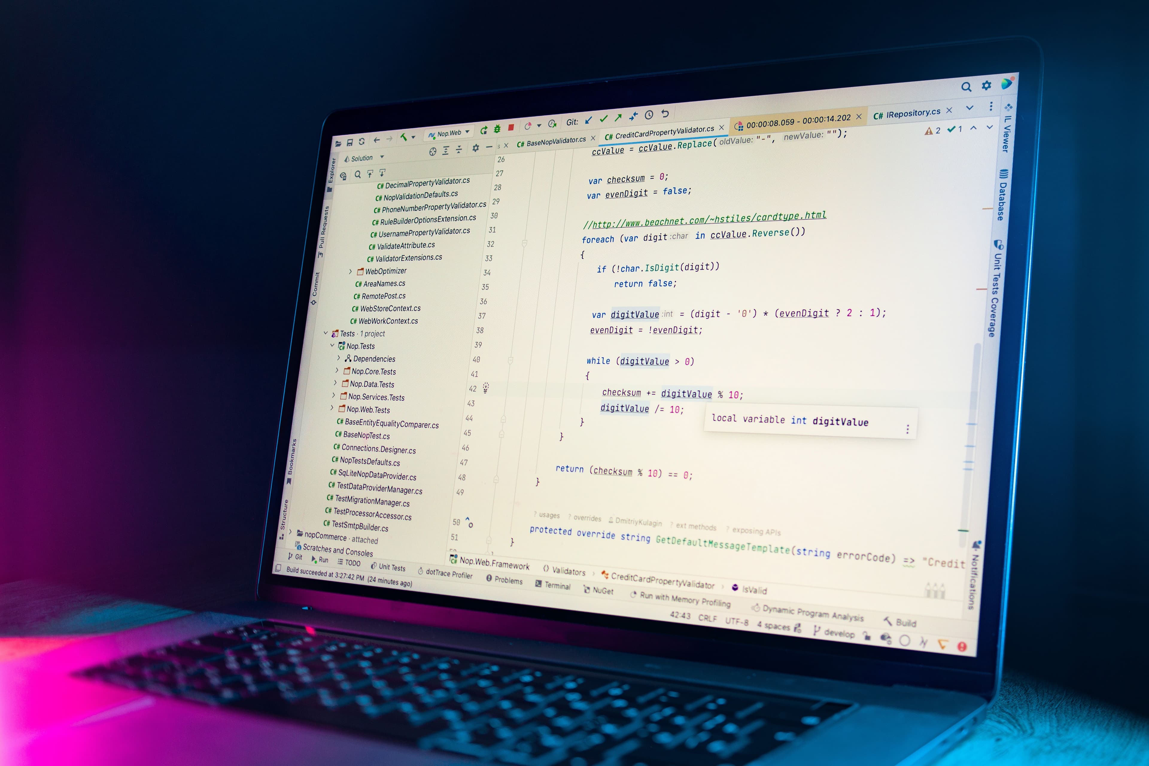Laptop com IDE exibindo código sob luzes magenta e azul