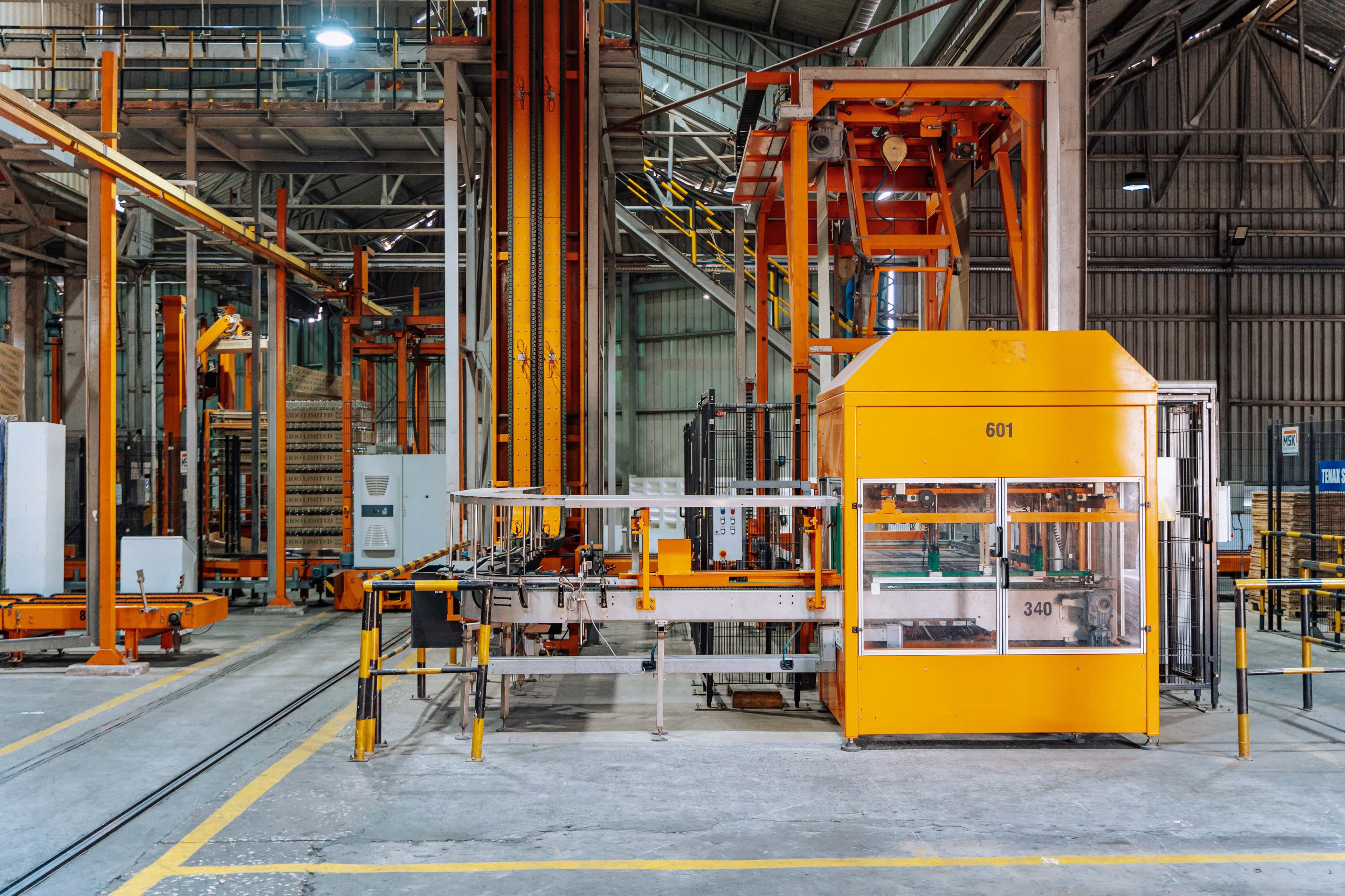 Robôs e máquinas em ambiente industrial com rotas demarcadas, simbolizando navegação com visão monocular