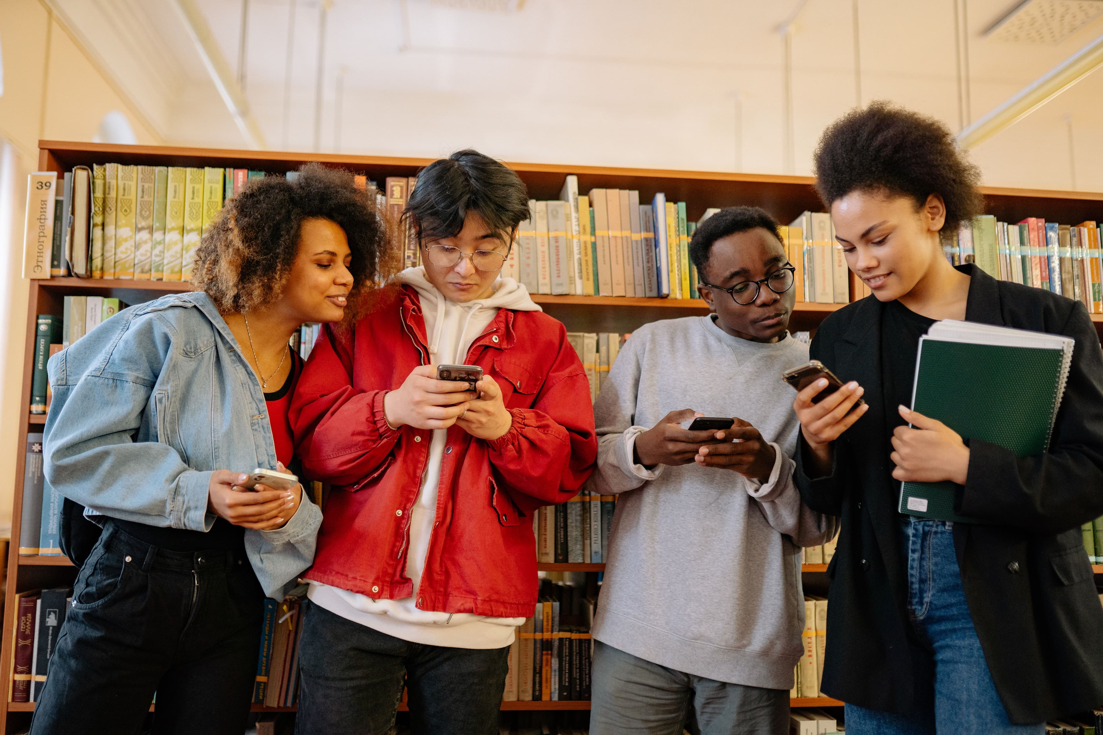 Grupo de pessoas usando smartphones em uma biblioteca durante workshop