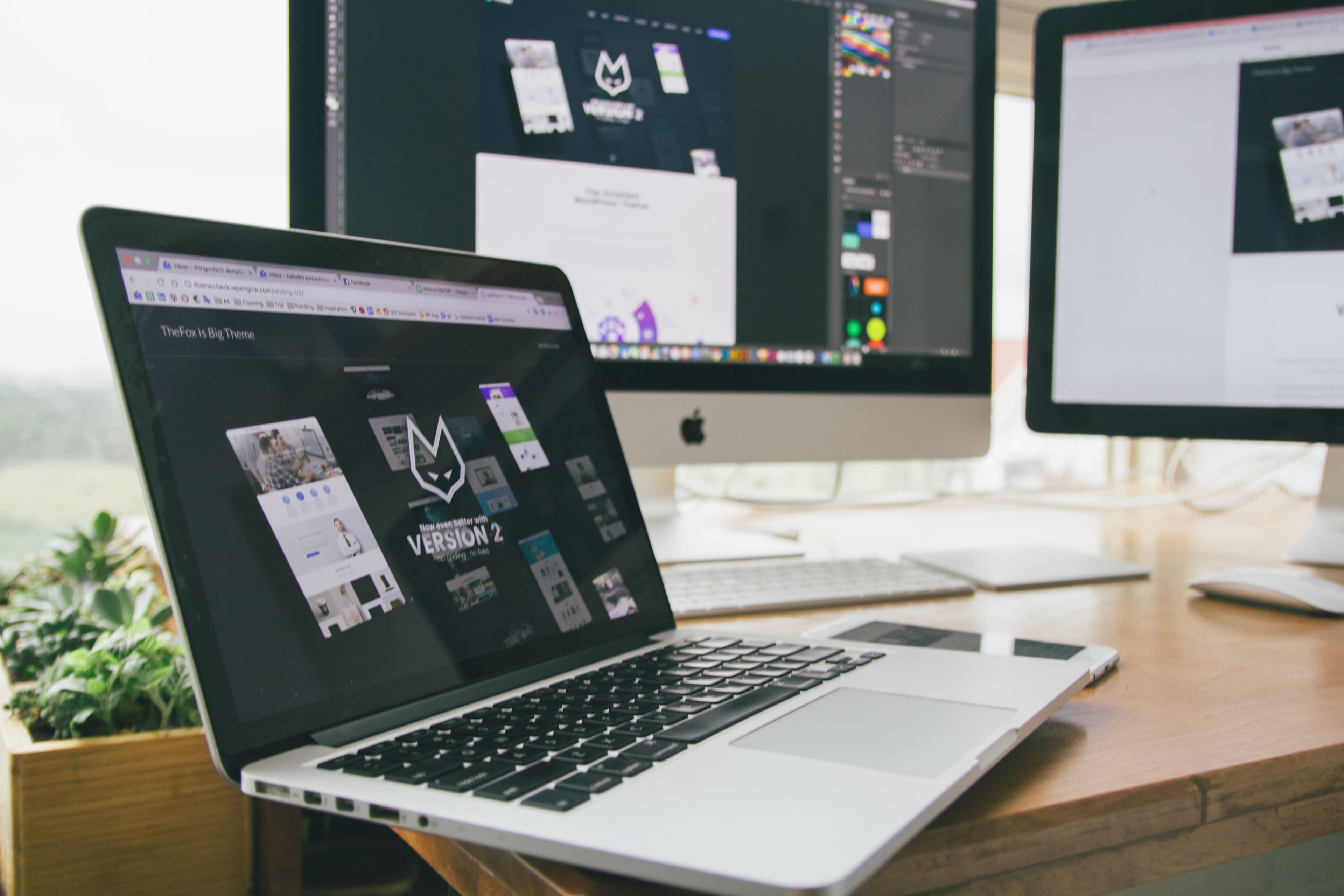 Workspace com laptop e monitores exibindo software de design