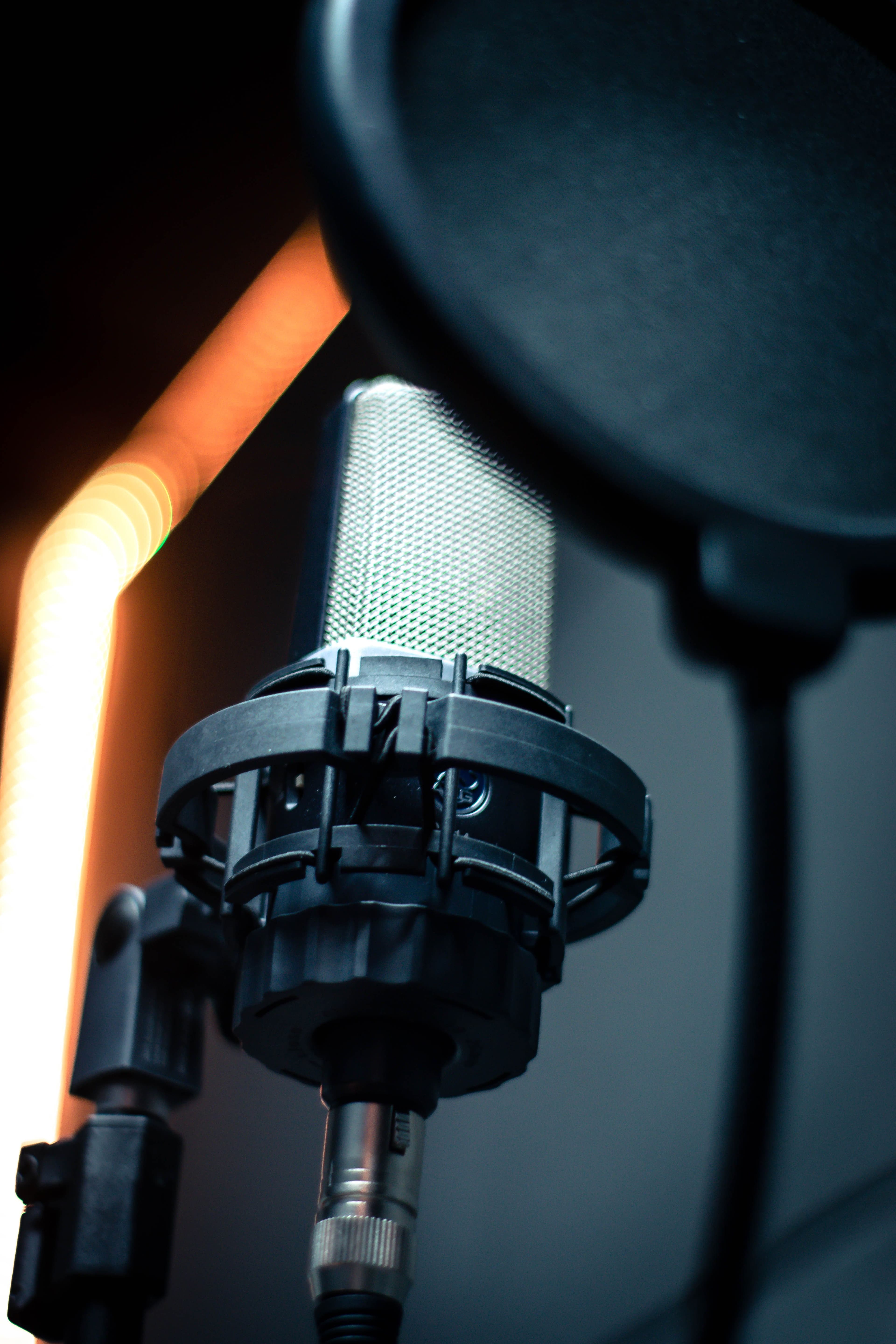 Microfone de estúdio com pop filter e iluminação baixa, simbolizando produção de voz com IA