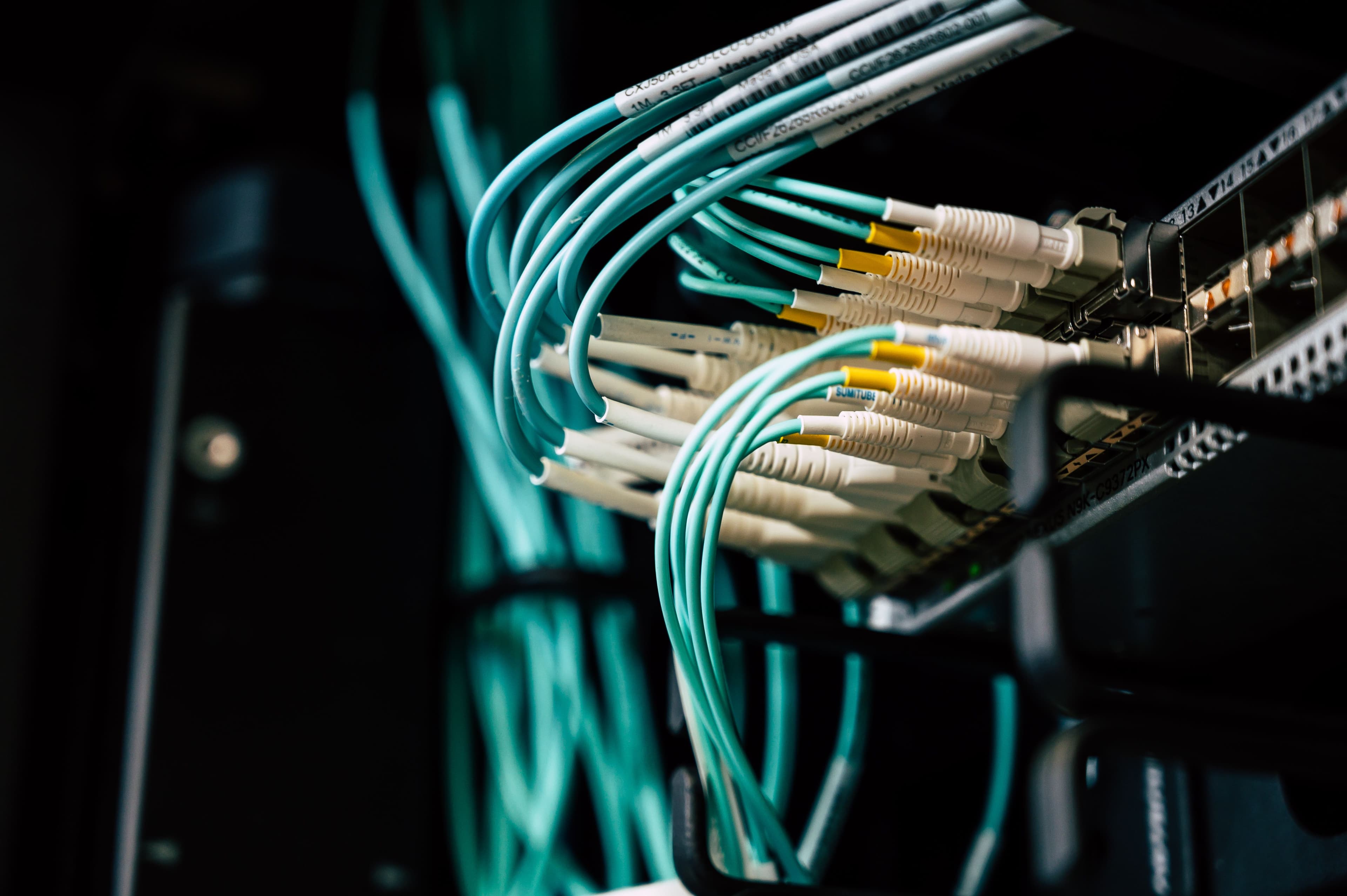 Cabos de rede conectados em rack de servidor, ilustrando infraestrutura para IA