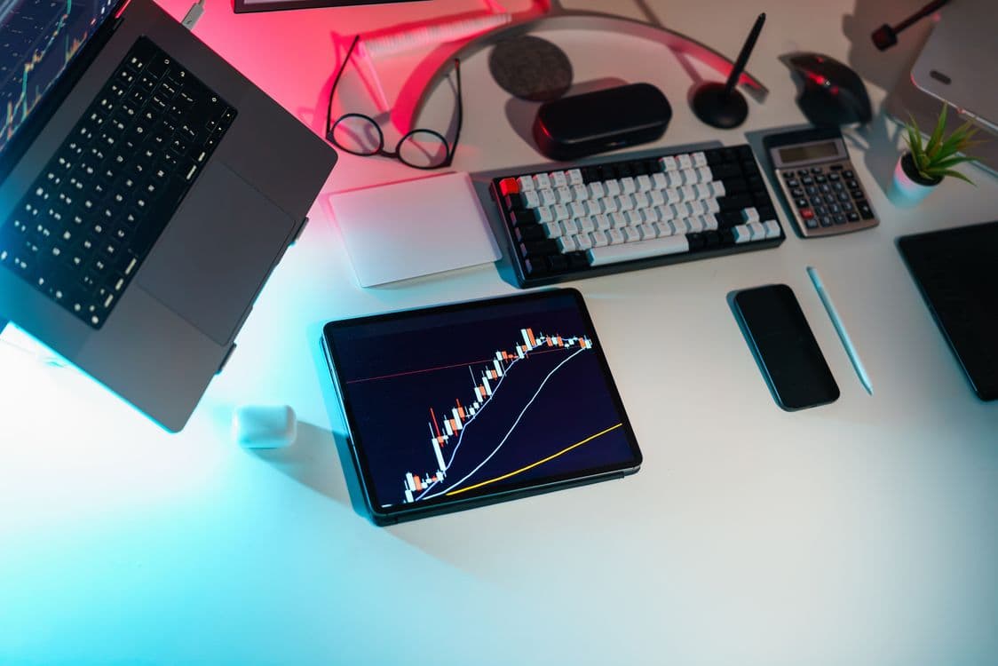 Mesa com dispositivos exibindo gráficos financeiros, representando análise de risco com IA