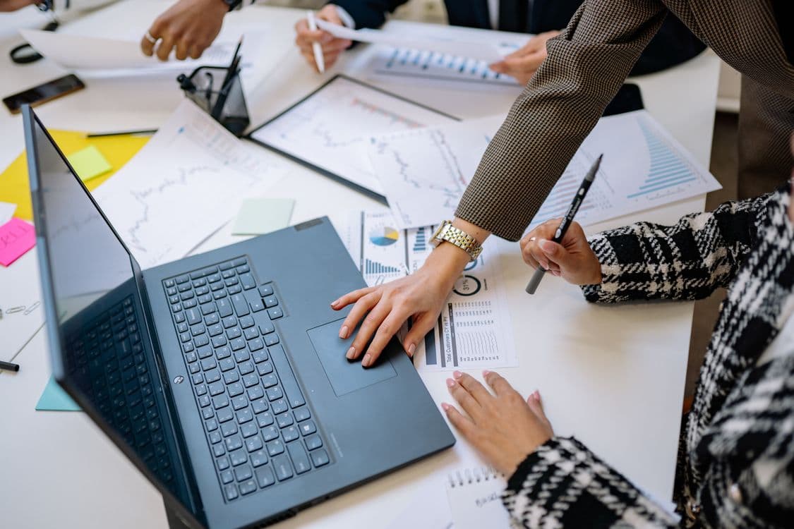 Mesa de reunião com laptop e gráficos representando criação de apresentações com IA