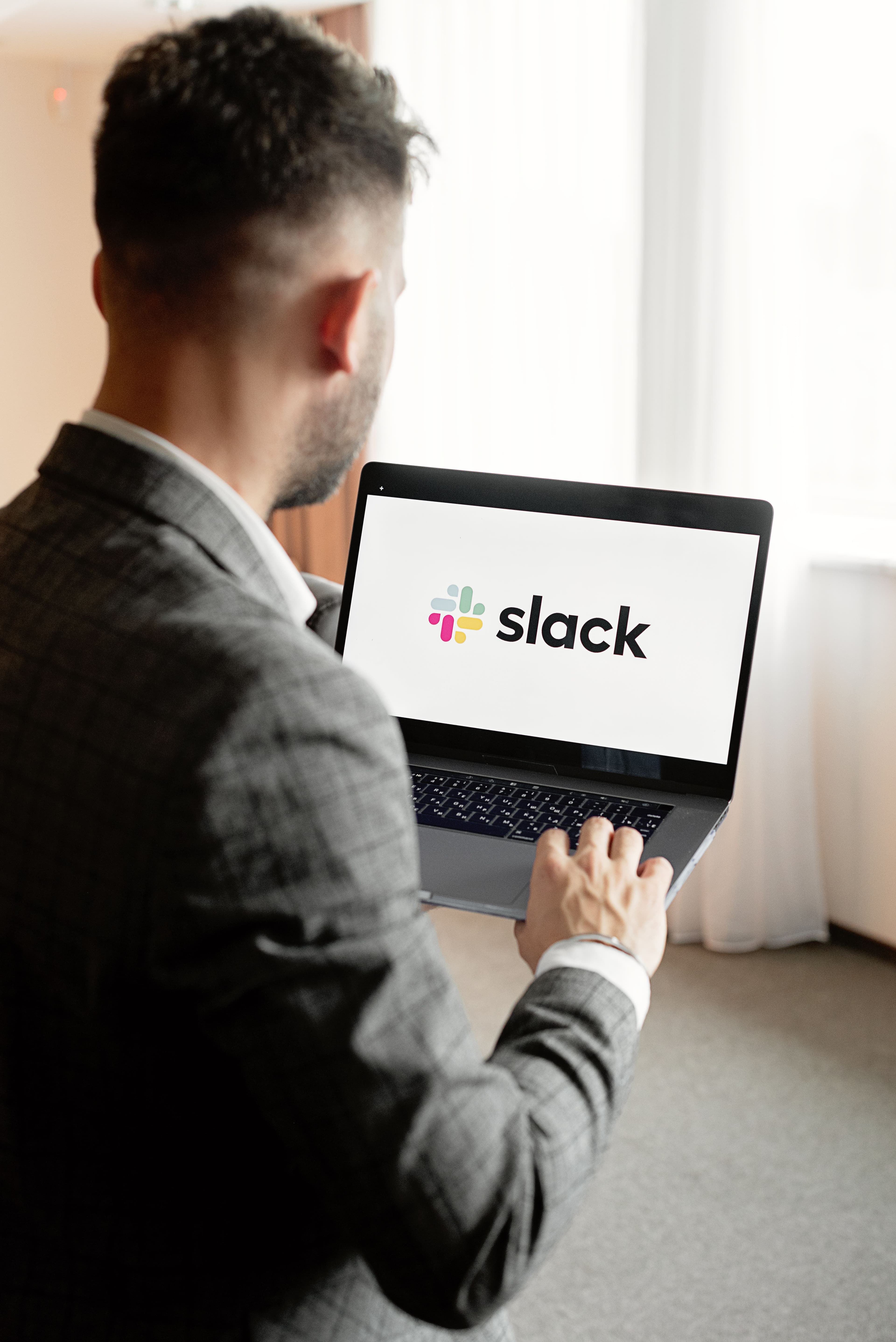 Profissional usando Slack no notebook, representando colaboração com IA