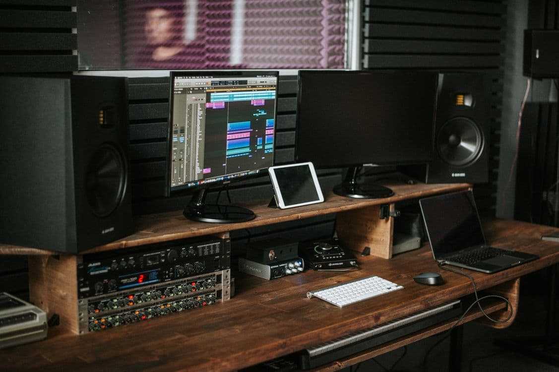 Faders de uma mesa de mixagem em close, representando produção musical