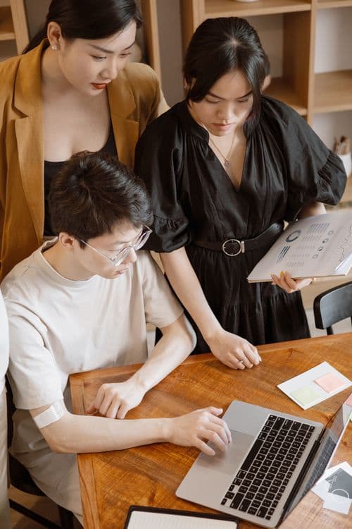 Equipe usando laptop em escritório, simbolizando adoção do Grok Bot