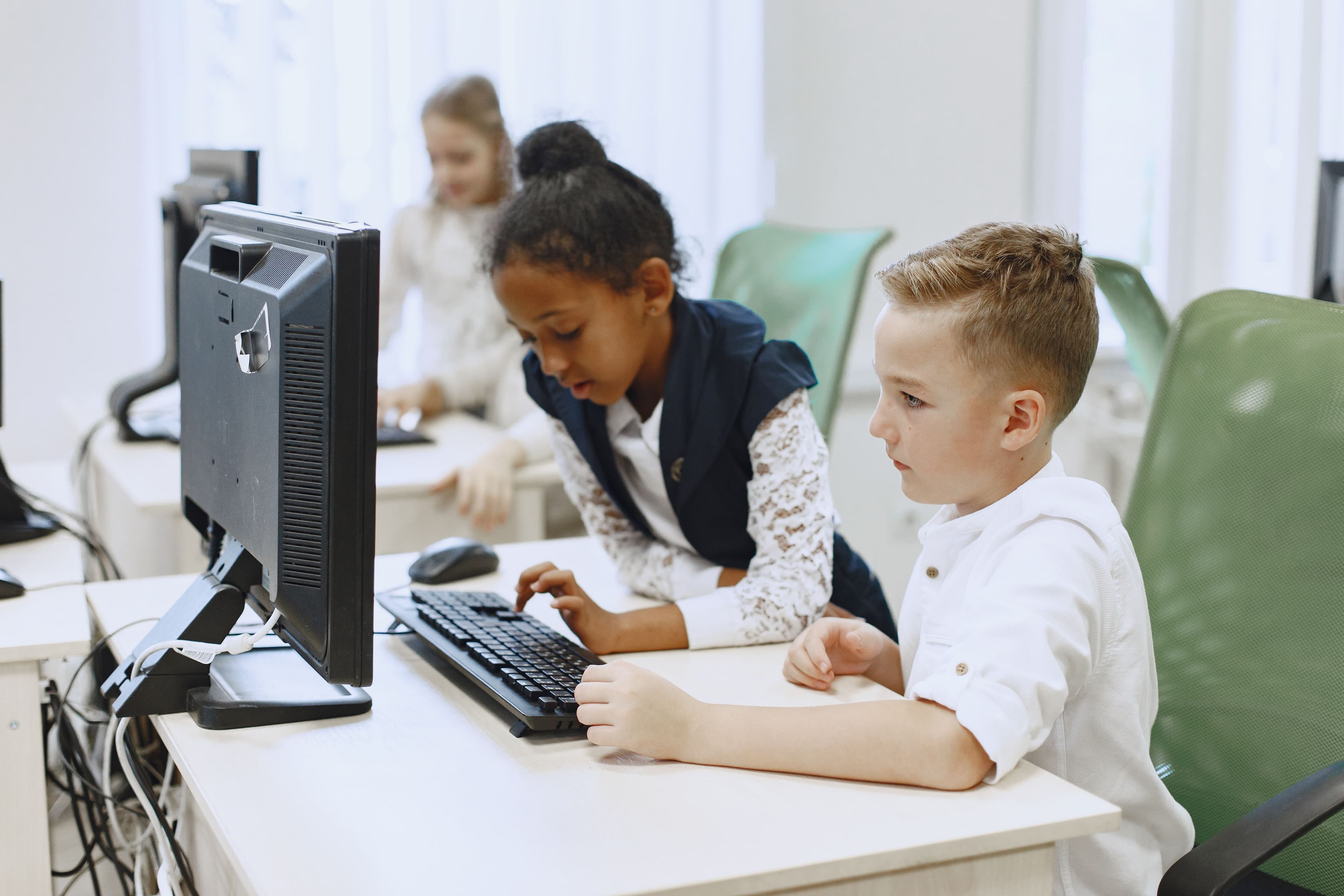Alunos em sala de aula usando computadores sob orientação da professora