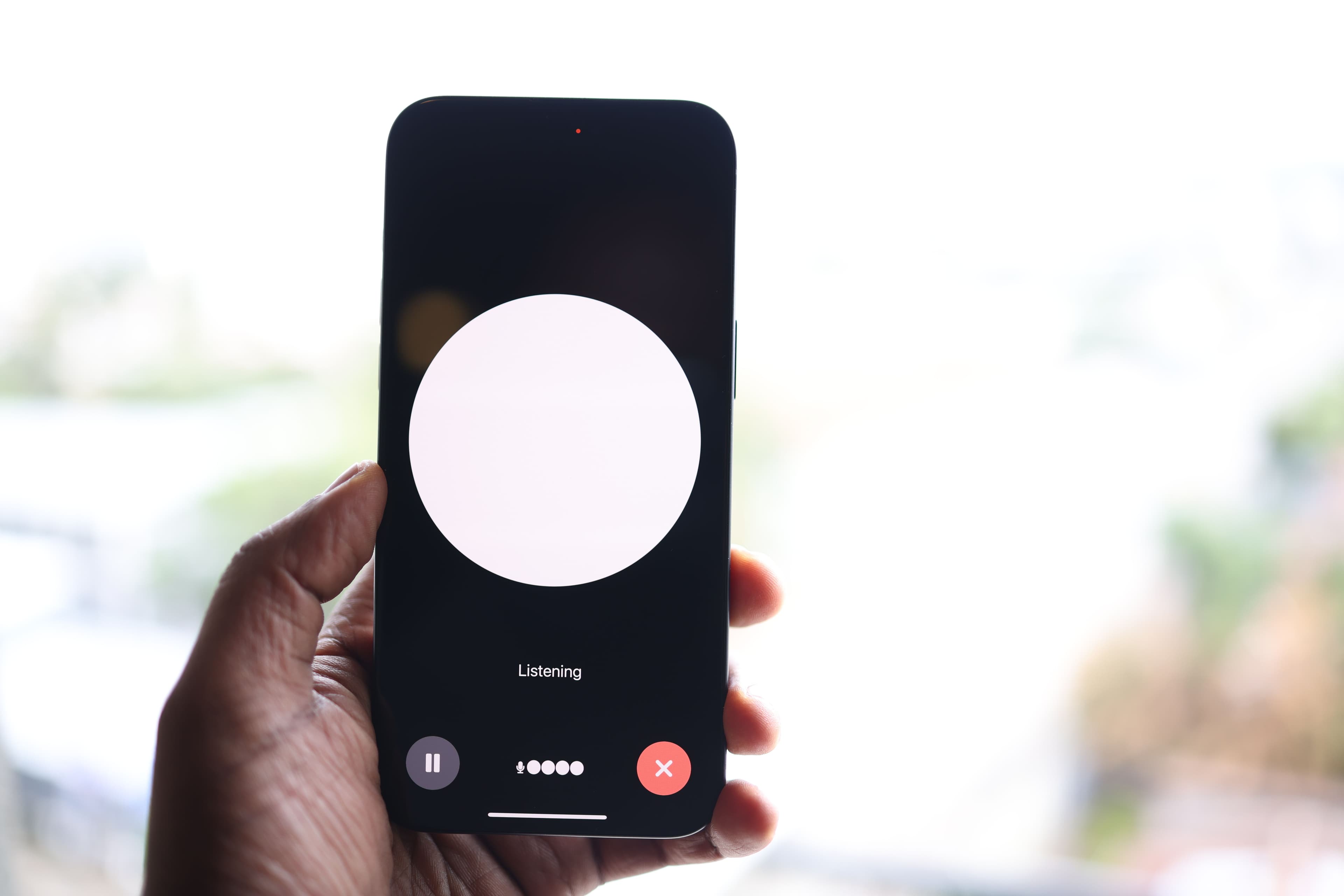 Mão segurando smartphone com interface de assistente por voz