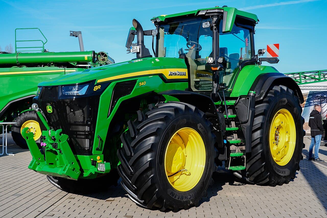 Trator John Deere 8R exibido em feira agrícola, visão frontal