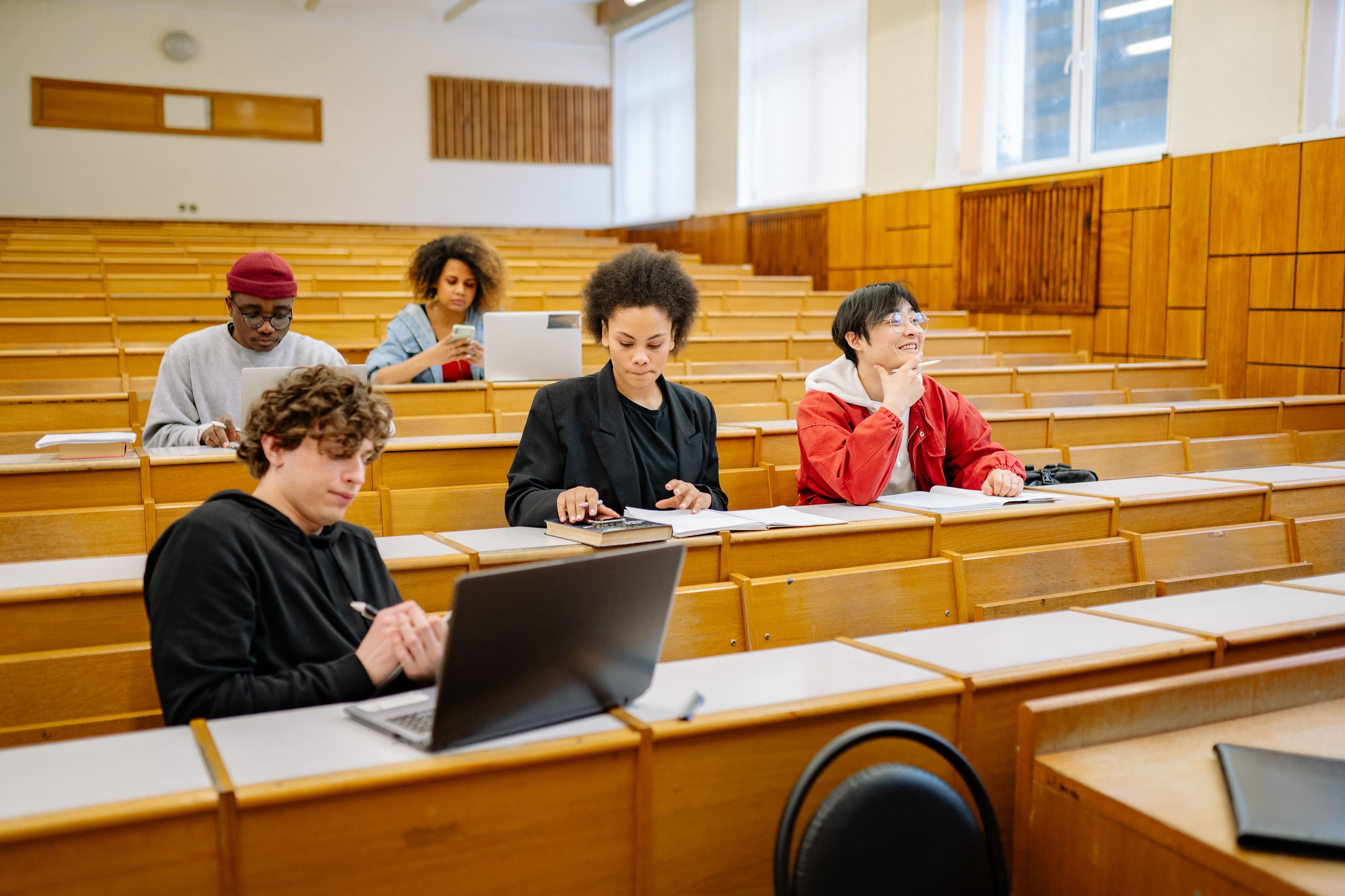 Estudantes em sala de aula usando laptops, em auditório universitário