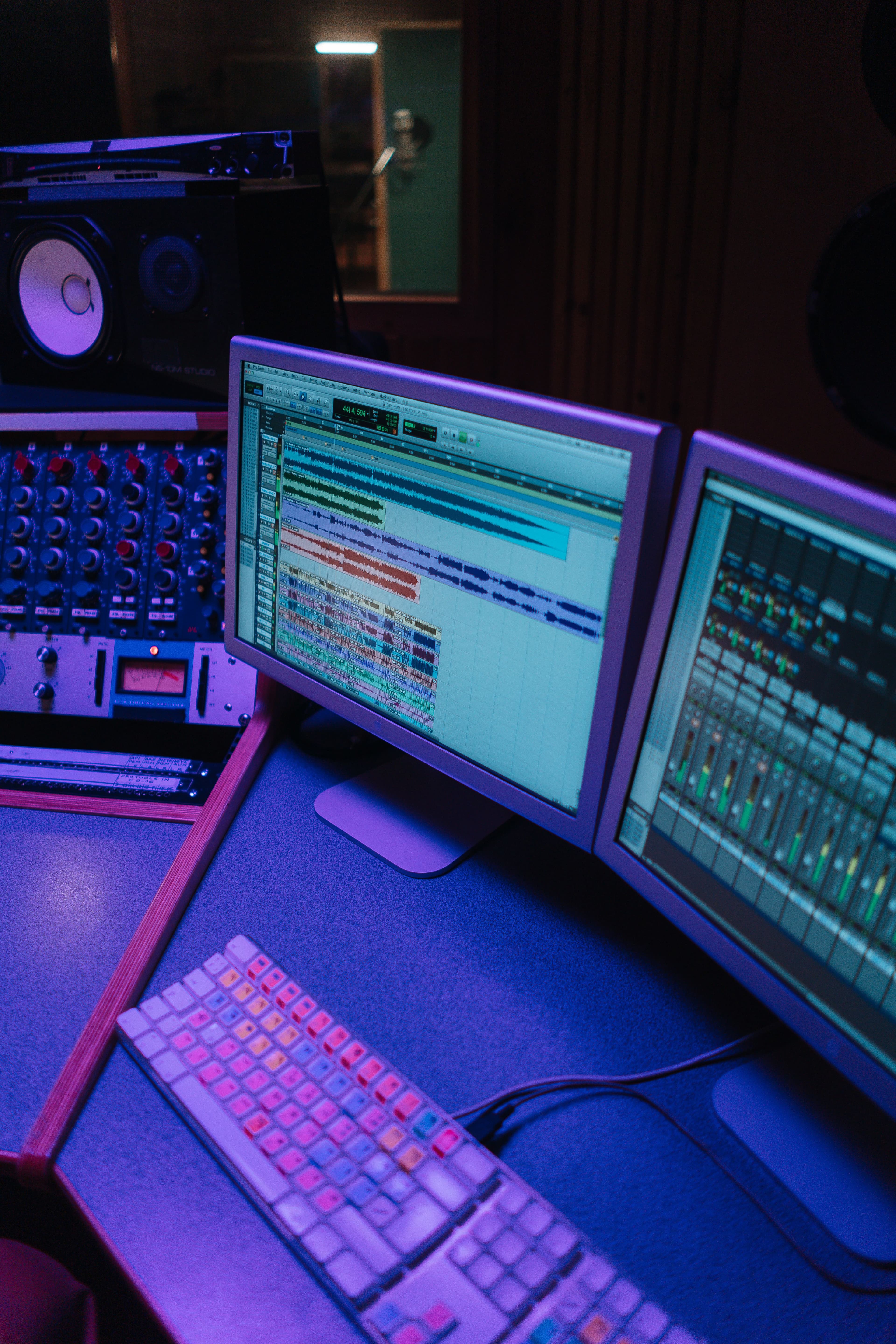 Estúdio de áudio com console de mixagem e telas de DAW