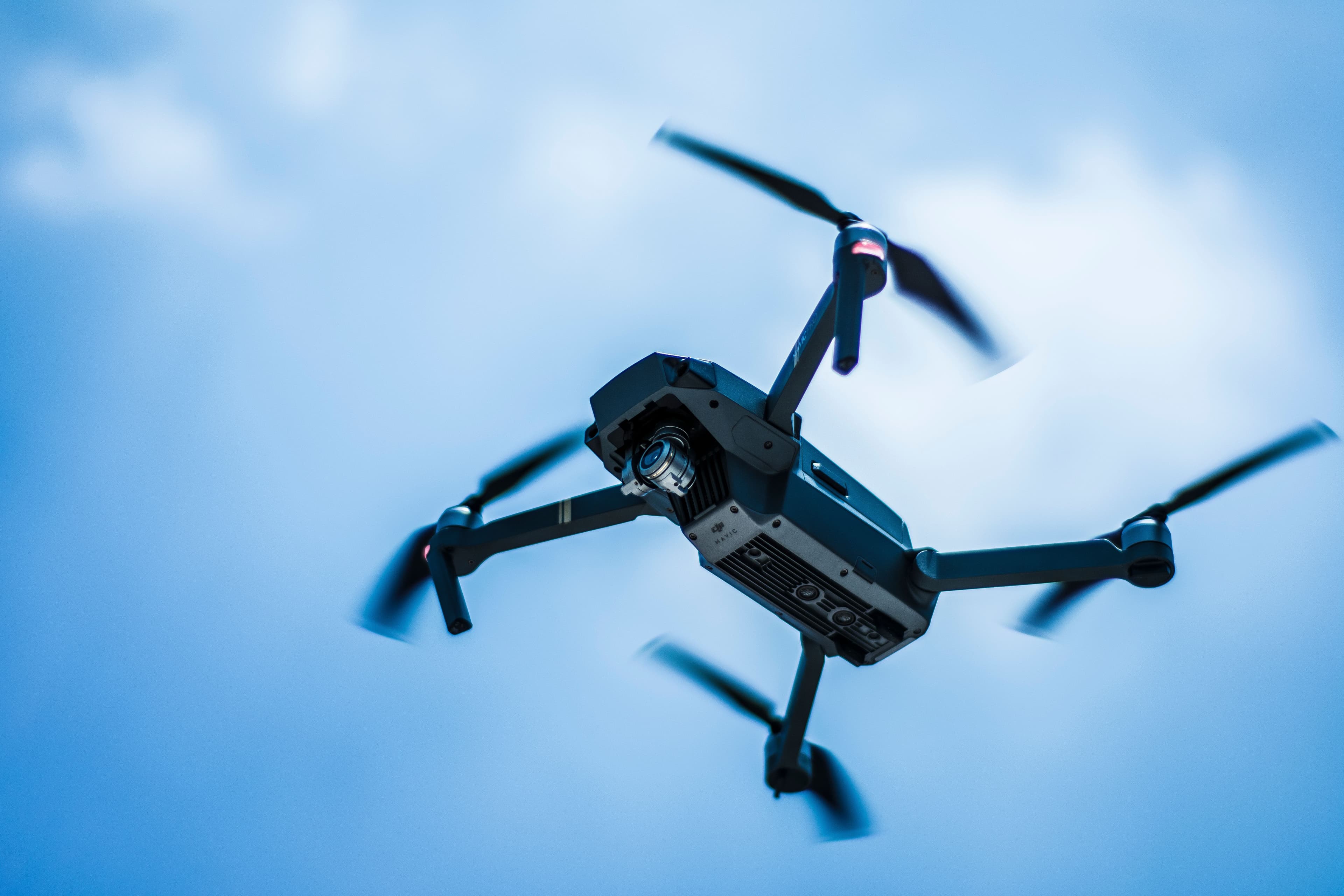 Drone quadricóptero em voo sob céu azul, close da câmera e rotores