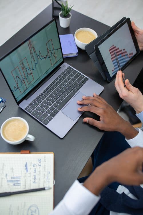 Profissionais analisando dashboards de marketing em laptop e tablet