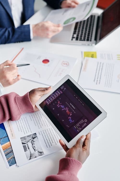 Assessores financeiros analisando dados em tablet com gráficos