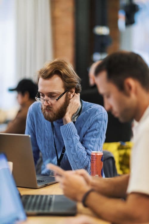 Profissionais colaborando em escritório com laptops, representando colegas de IA