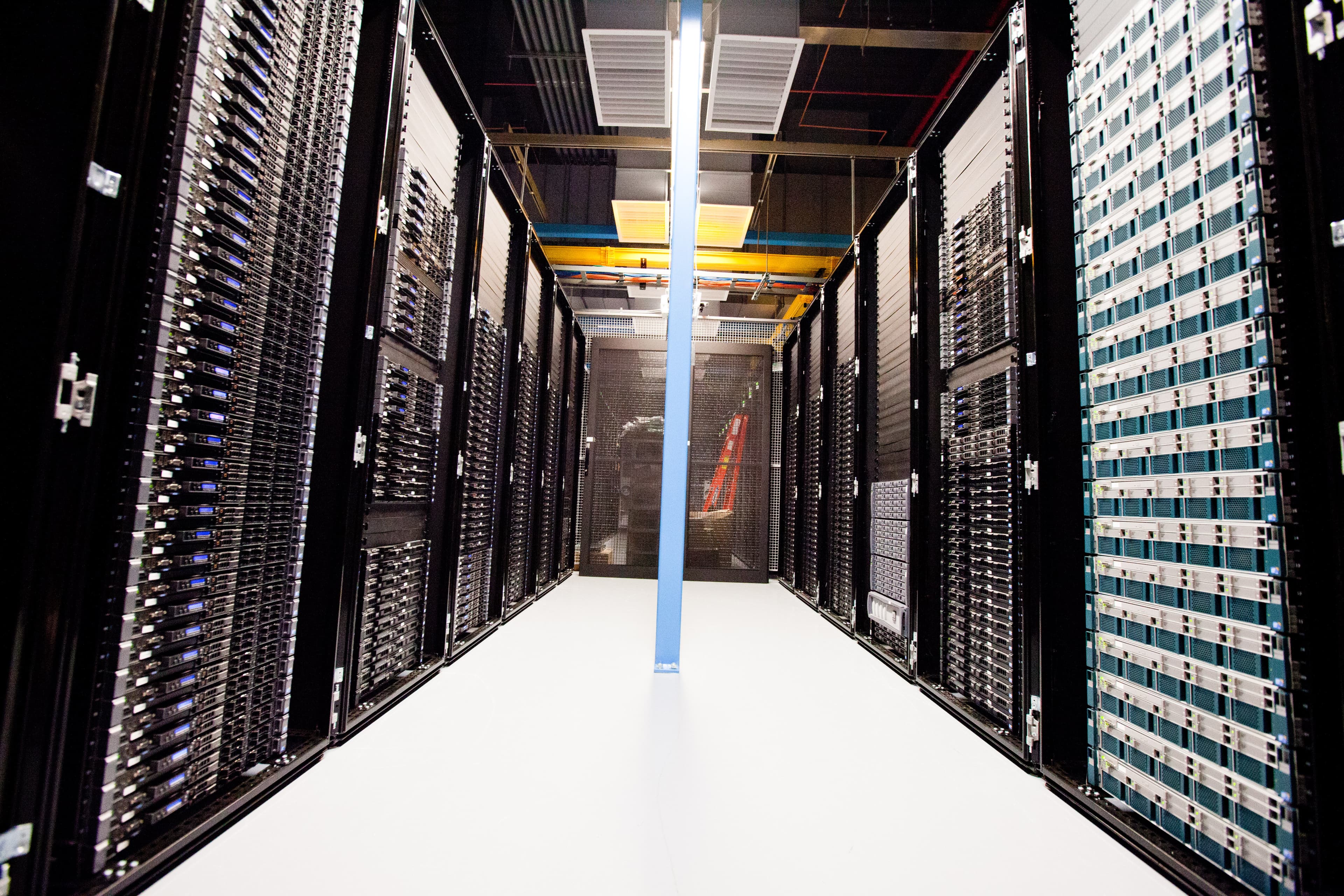 Corredor de racks de servidores em data center, luzes e cabos visíveis
