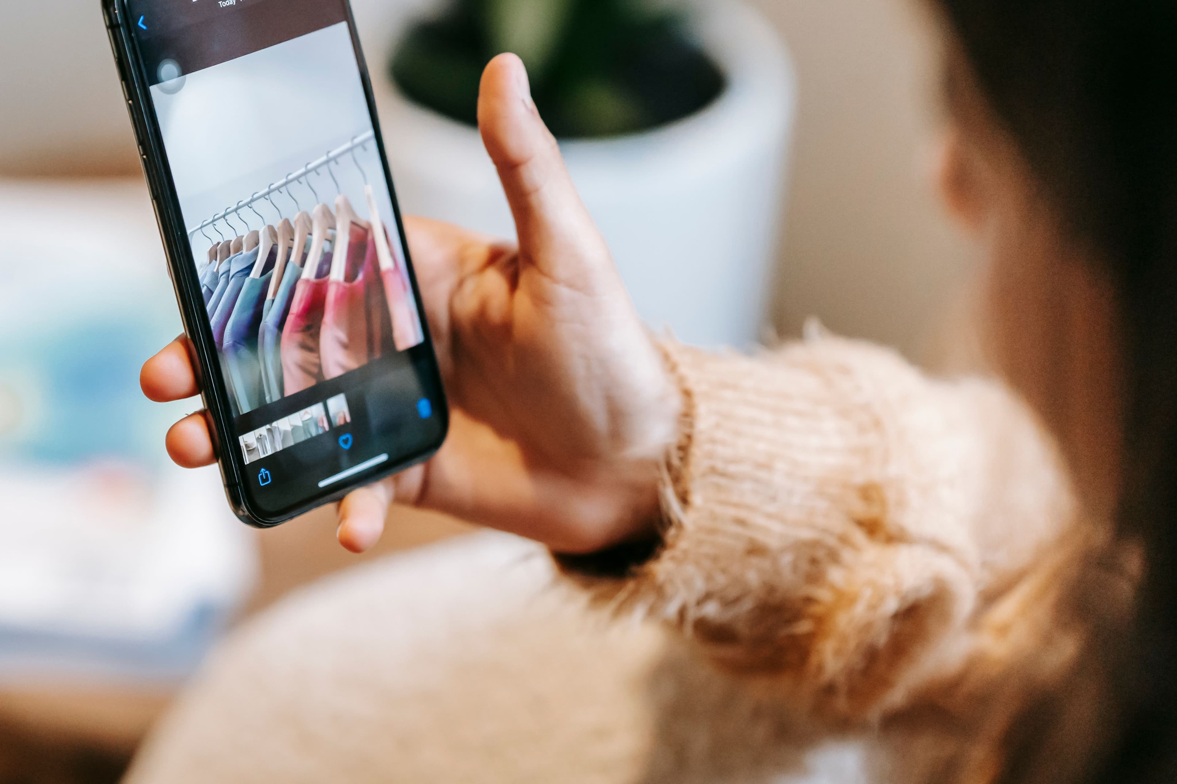 Pessoa usando o celular para fotografar roupas em um closet, representando o uso de app de moda com IA