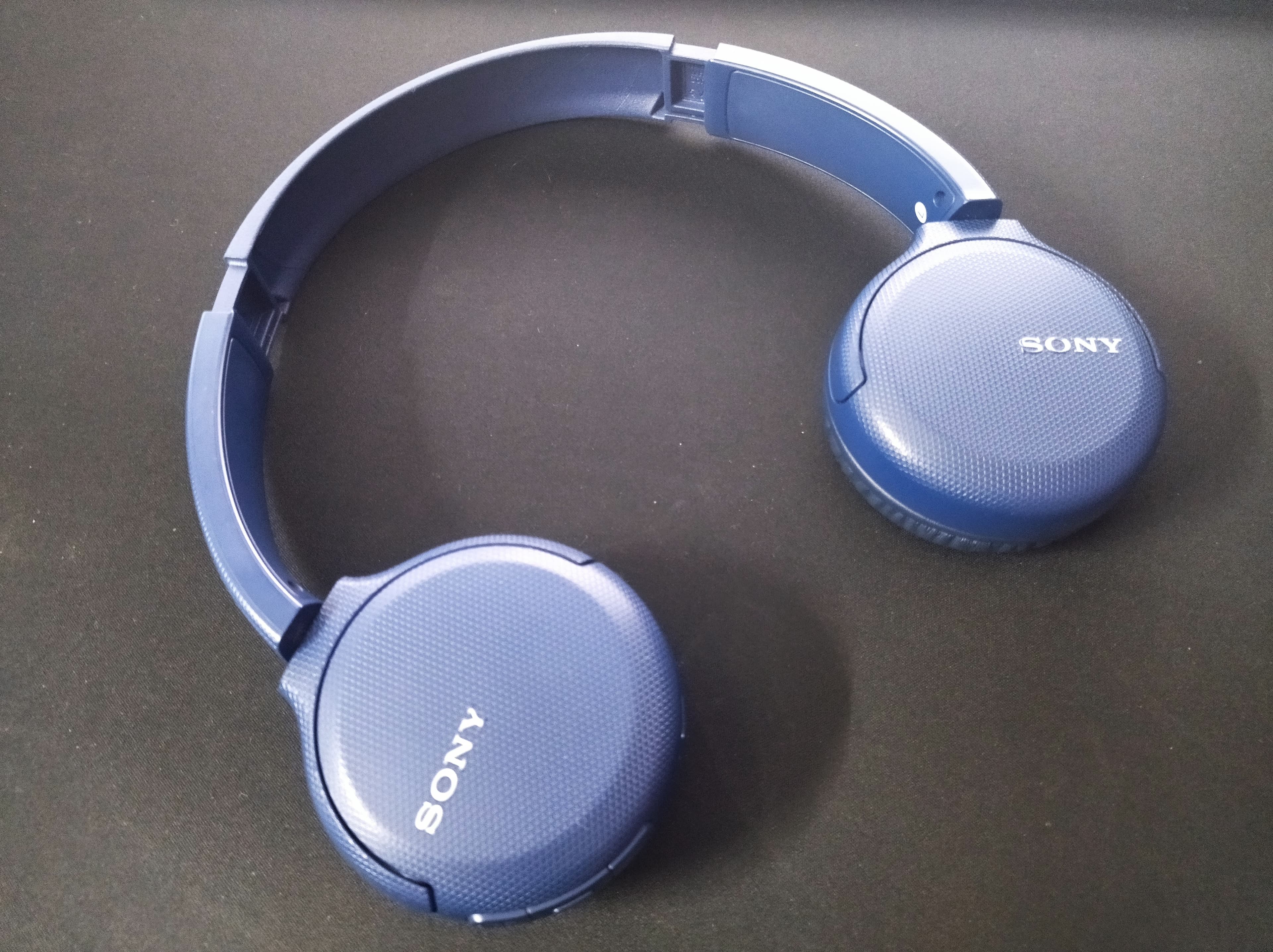 Fones de ouvido Sony azuis sobre superfície escura, ilustrando áudio e tradução em tempo real