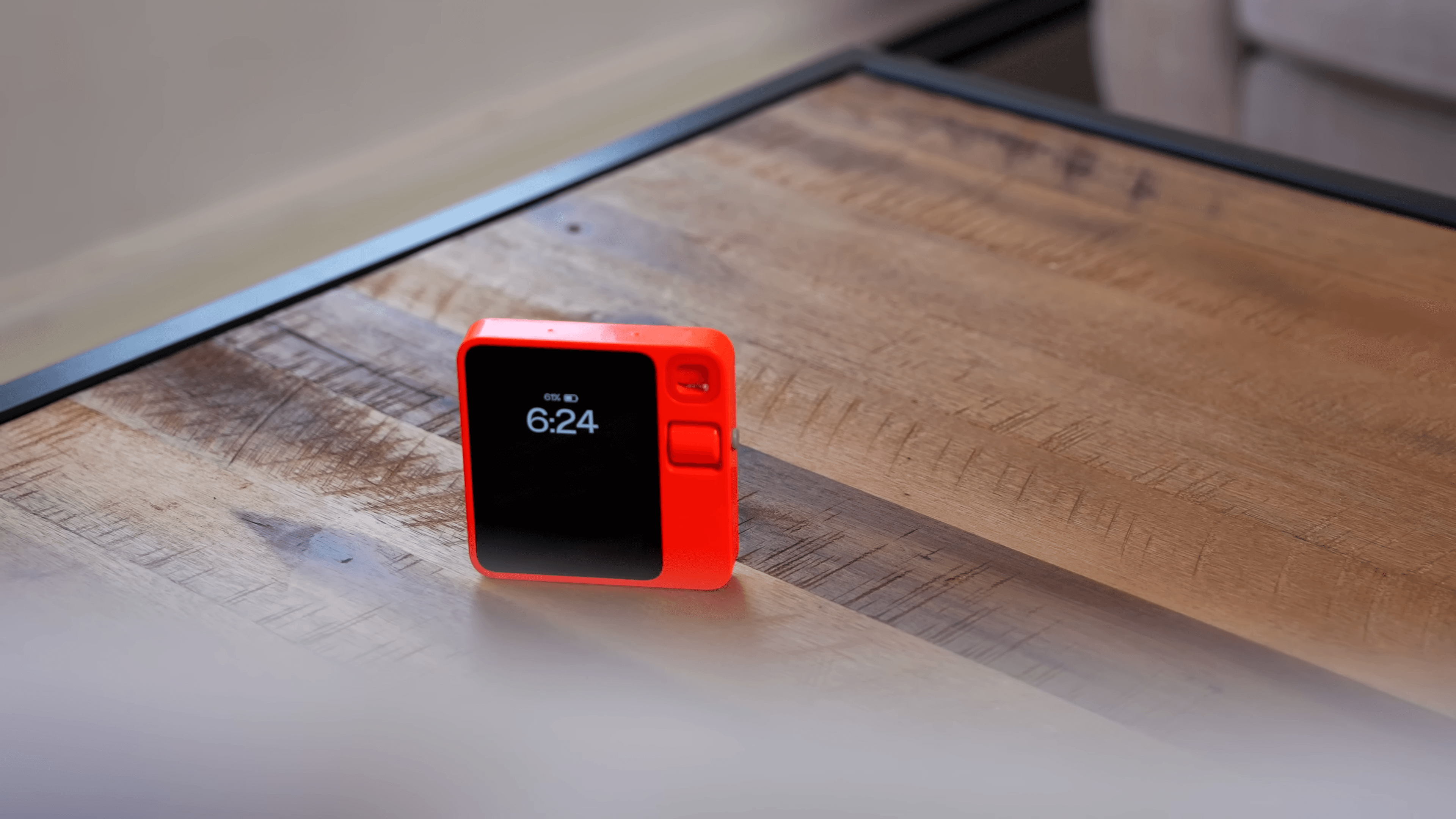 Rabbit r1 em mesa de madeira com tela ligada