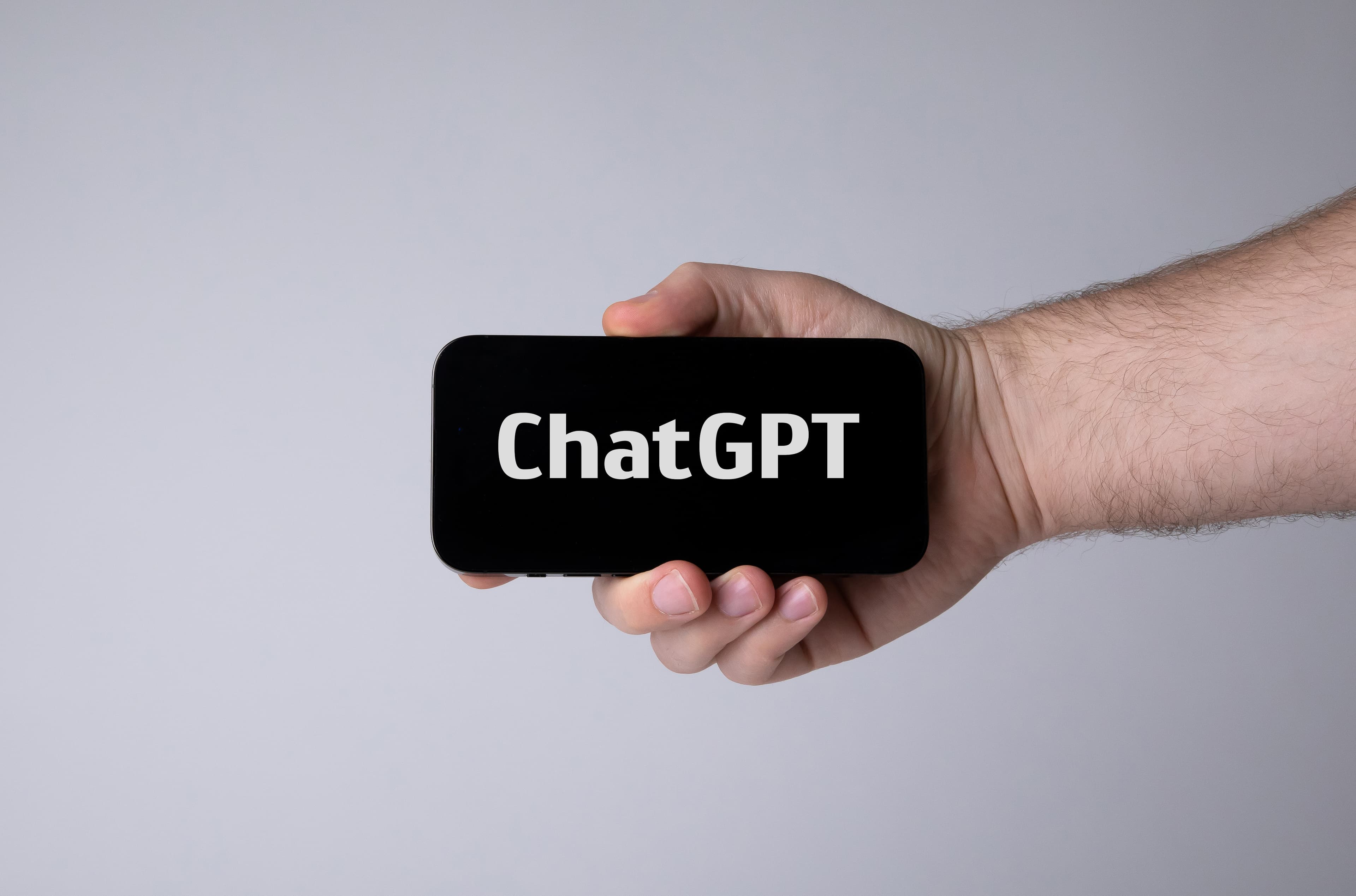 Mão segurando smartphone com a palavra ChatGPT na tela