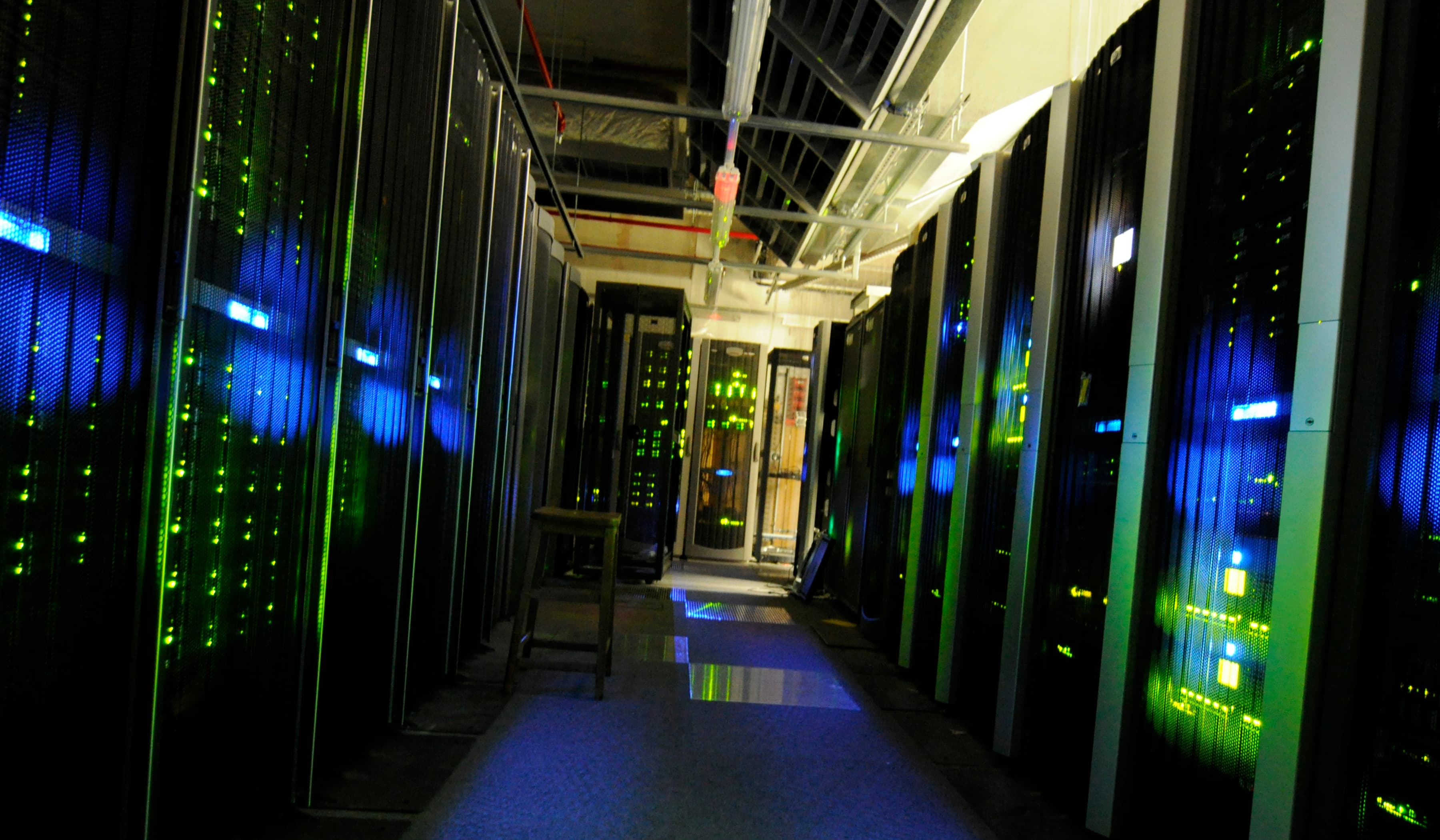 Corredor de data center com racks e iluminação azul